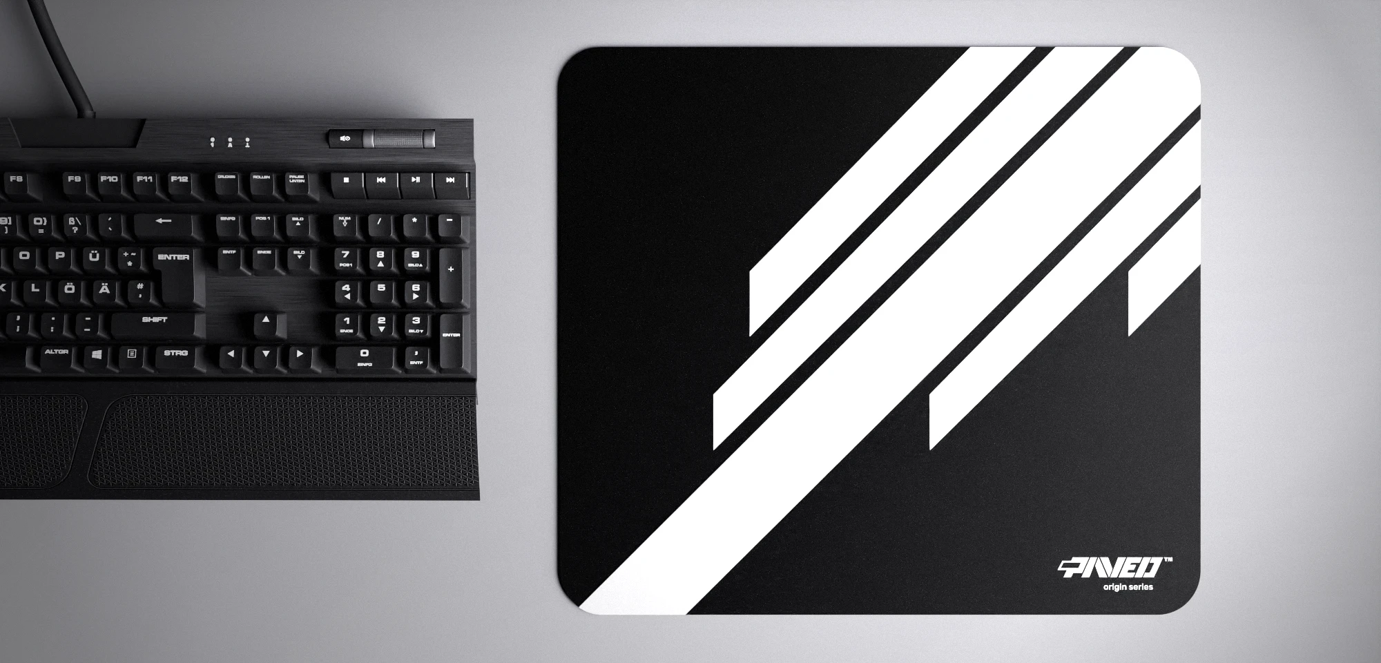 Top view of Night Blade Runner M size mousepad 360mm x 320mm right-handed variant with diagonal stripe design in white and black, hydrophobic easy-to-clean surface with antimicrobial properties, shown with full-size mechanical keyboard for scale, 600% lighter with no rubbery odour base, durable stitch-free finish.