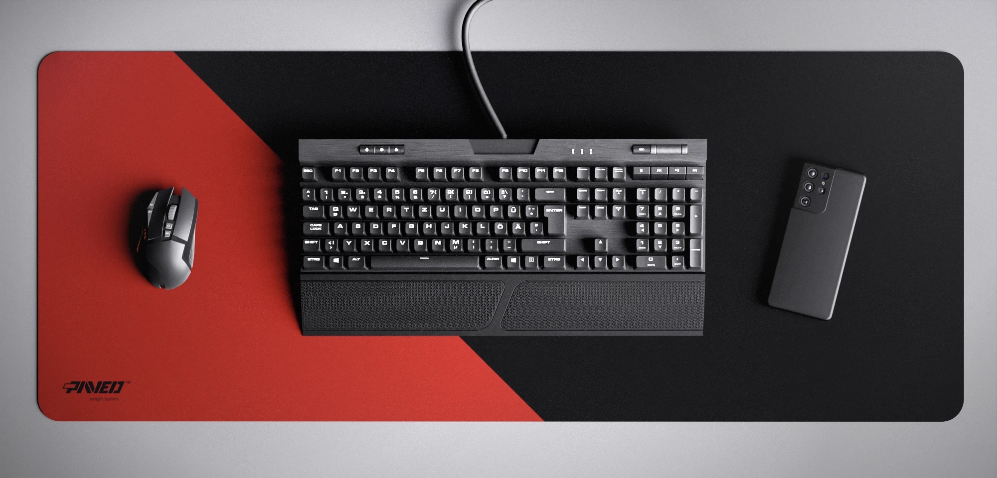 Top view of Imperial Edge Runner XXL deskmat 1000mm x 400mm left-handed variant featuring diagonal split design in red and black, water-resistant antimicrobial polyester surface, shown with full-size mechanical keyboard, gaming mouse, and smartphone for scale, ultra-lightweight odour-free AreoFlex microruber base, stitch-free professional finish.