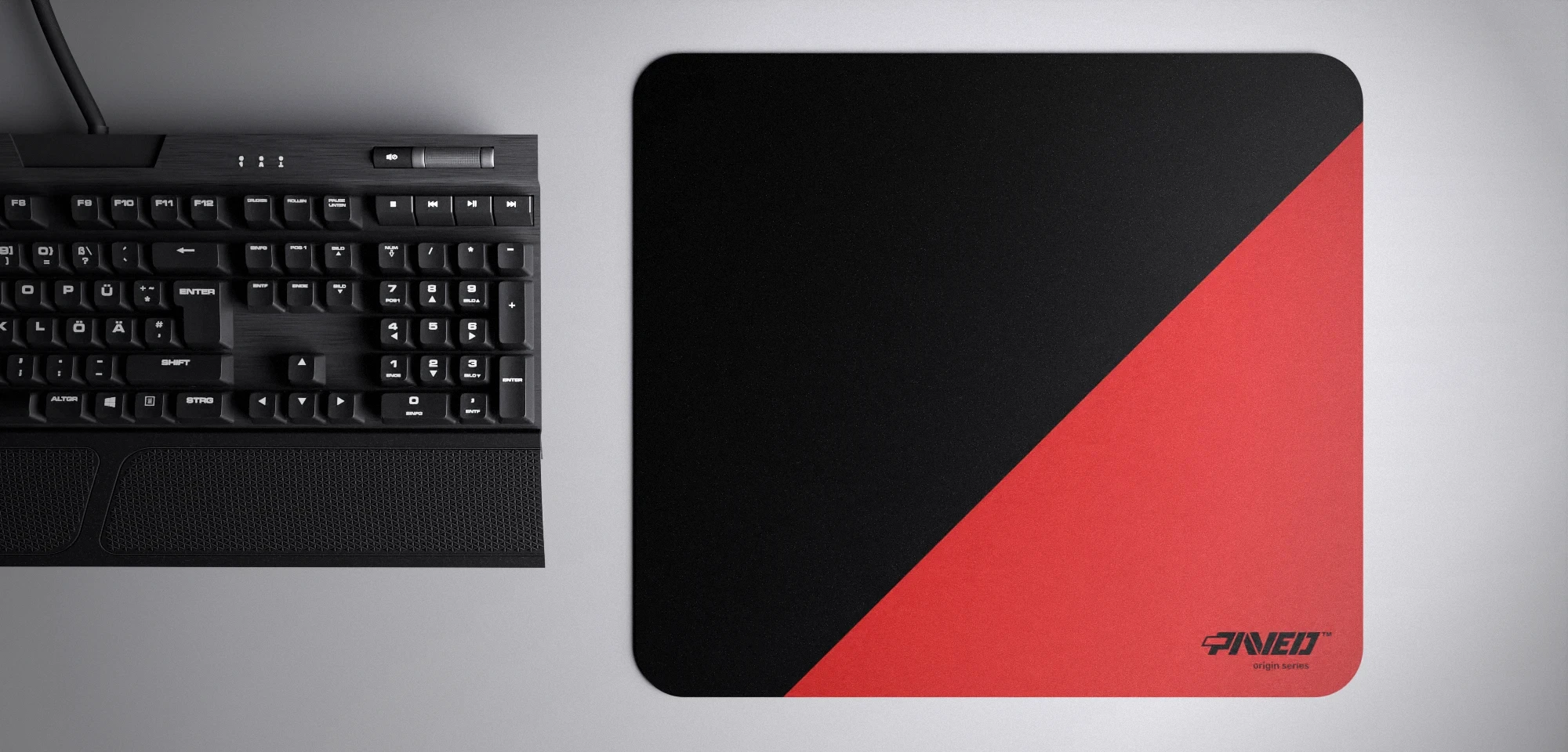 Top view of Imperial Edge Runner M size mousepad 360mm x 320mm right-handed variant with diagonal split design in red and black, hydrophobic easy-to-clean surface with antimicrobial properties, shown with full-size mechanical keyboard for scale, 600% lighter with no rubbery odour base, durable stitch-free finish.