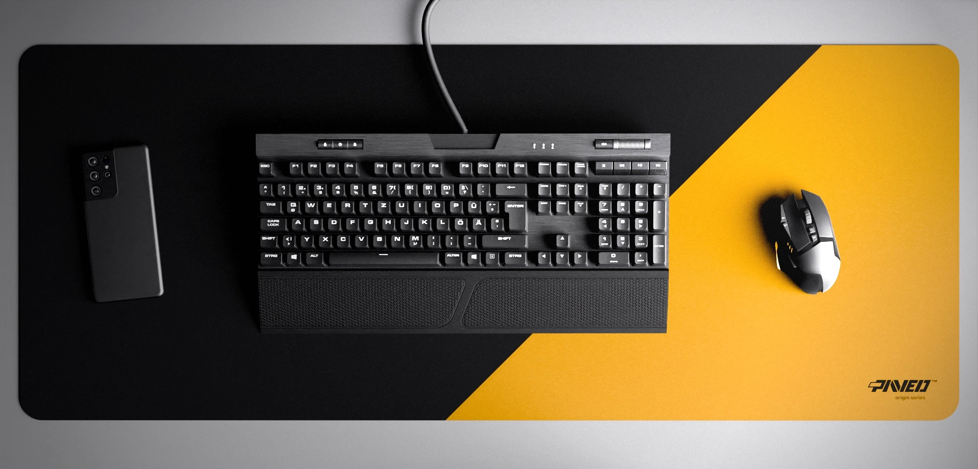 Top view of Desert Edge Runner XXL deskmat 1000mm x 400mm right-handed variant with minimalistic diagonal split design in deep yellow and black, hydrophobic easy-to-clean antimicrobial surface, shown with full-size mechanical keyboard, gaming mouse, and smartphone for scale, 600% lighter non-slip base with no rubbery smell, durable stitch-free edges.