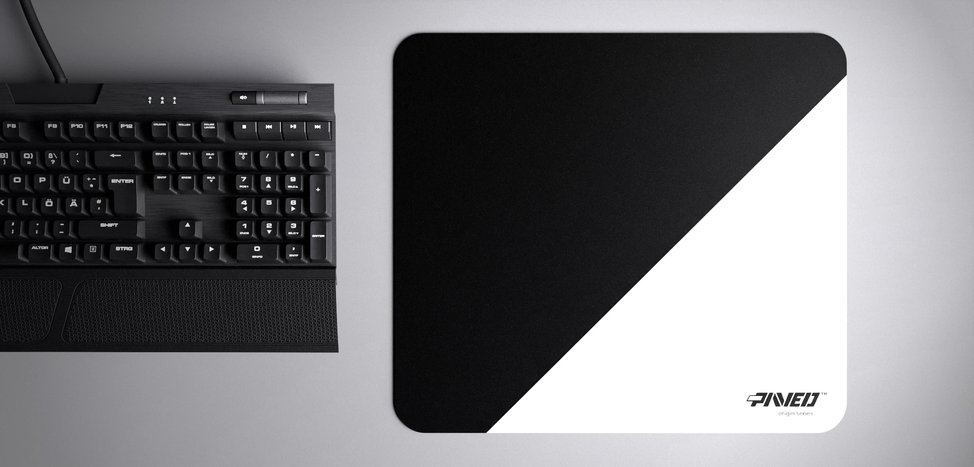 Top view of Polar Edge Runner M size mousepad 360mm x 320mm right-handed variant with diagonal split design in white and black, hydrophobic easy-to-clean surface with antimicrobial properties, shown with full-size mechanical keyboard for scale, 600% lighter with no rubbery odour base, durable stitch-free finish.