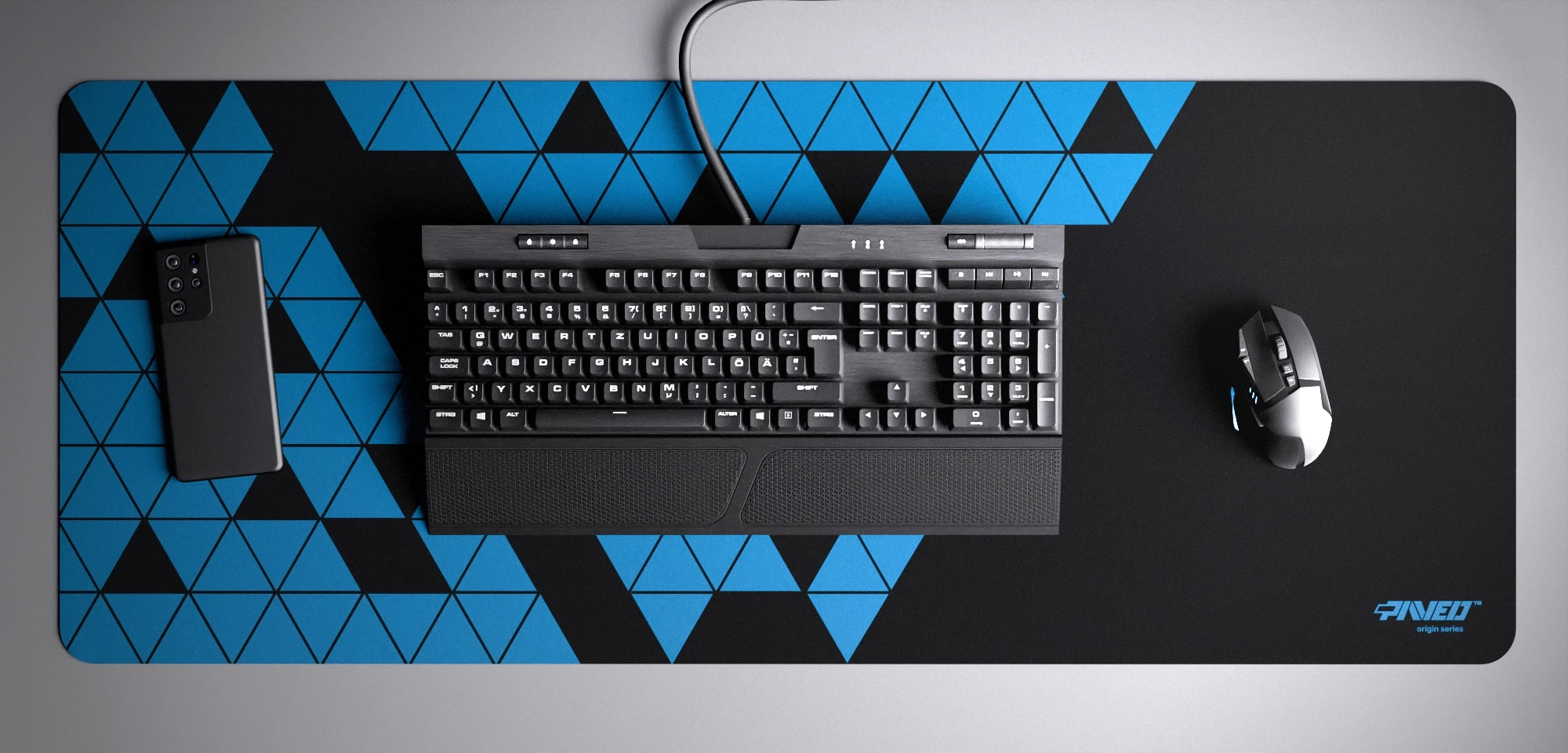 Top view of Night Sky Prism XXL deskmat 1000mm x 400mm right-handed variant with minimalistic geometric triangular prism pattern in sky blue and black, hydrophobic easy-to-clean antimicrobial surface, shown with full-size mechanical keyboard, gaming mouse, and smartphone for scale, 600% lighter non-slip base with no rubbery smell, durable stitch-free edges.