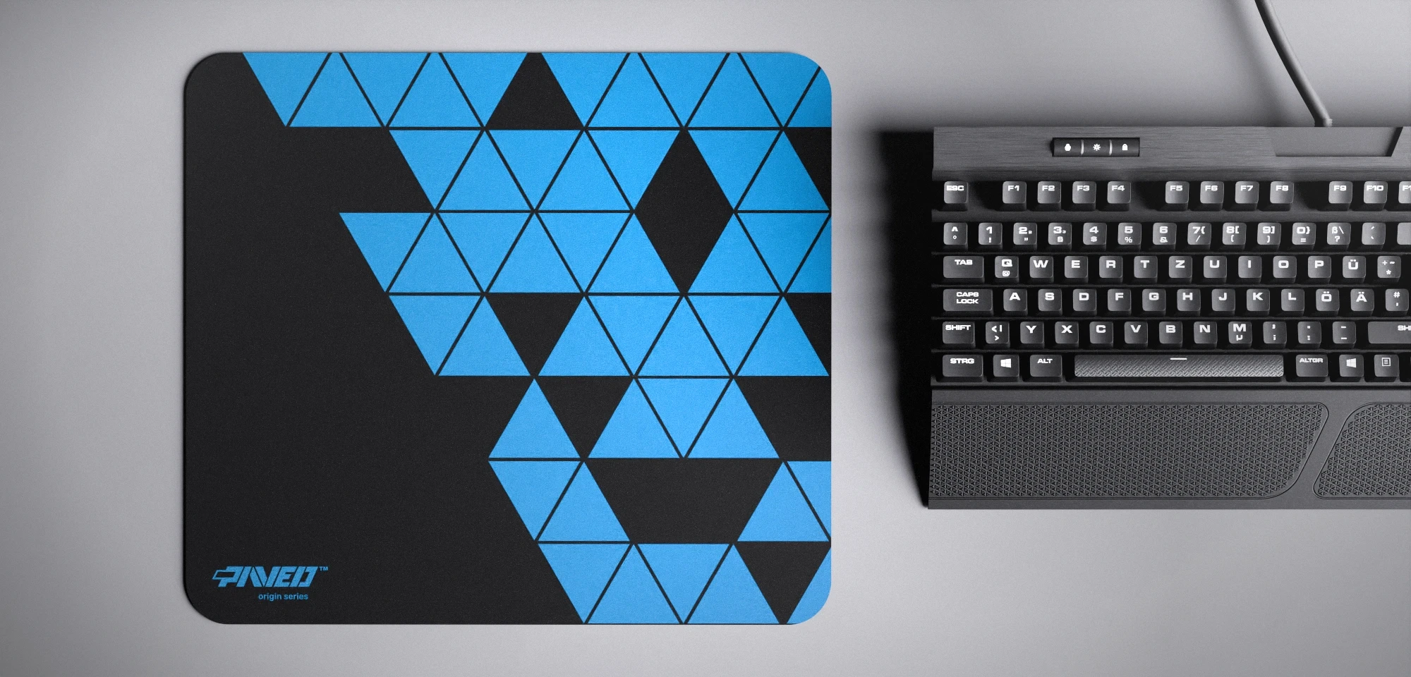 Top view of Night Sky Prism M size mousepad 360mm x 320mm left-handed variant with minimalistic sky blue triangular prism pattern on black background, water-resistant antimicrobial polyester surface, shown with full-size mechanical keyboard for scale, ultra-lightweight odour-free AreoFlex base, stitch-free edges.