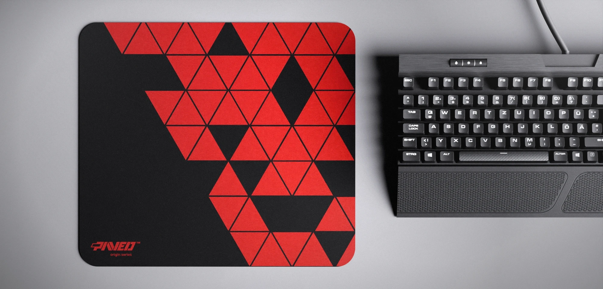 Top view of Night Imperial Prism M size mousepad 360mm x 320mm left-handed variant with minimalistic red triangular prism pattern on black background, water-resistant antimicrobial polyester surface, shown with full-size mechanical keyboard for scale, ultra-lightweight odour-free AreoFlex base, stitch-free edges.