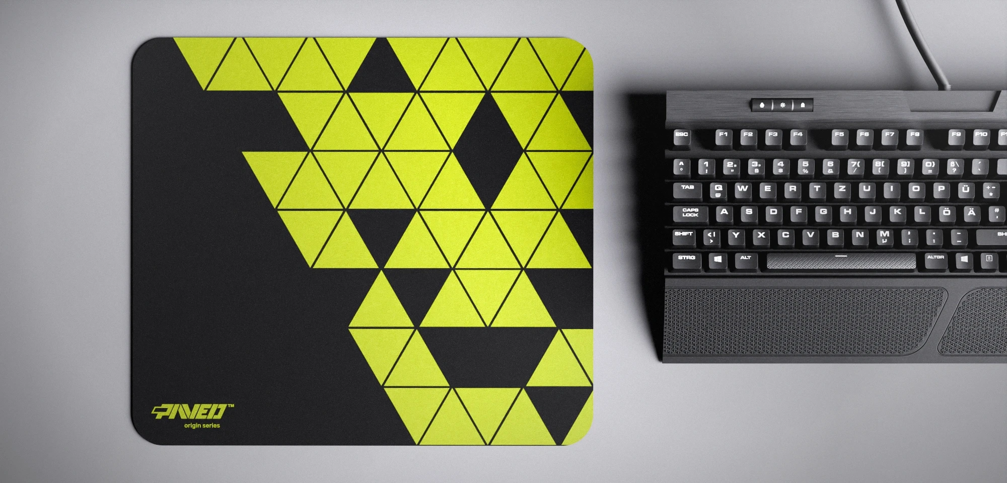 Top view of Night Toxic Prism M size mousepad 360mm x 320mm left-handed variant with minimalistic light green triangular prism pattern on black background, water-resistant antimicrobial polyester surface, shown with full-size mechanical keyboard for scale, ultra-lightweight odour-free AreoFlex base, stitch-free edges.