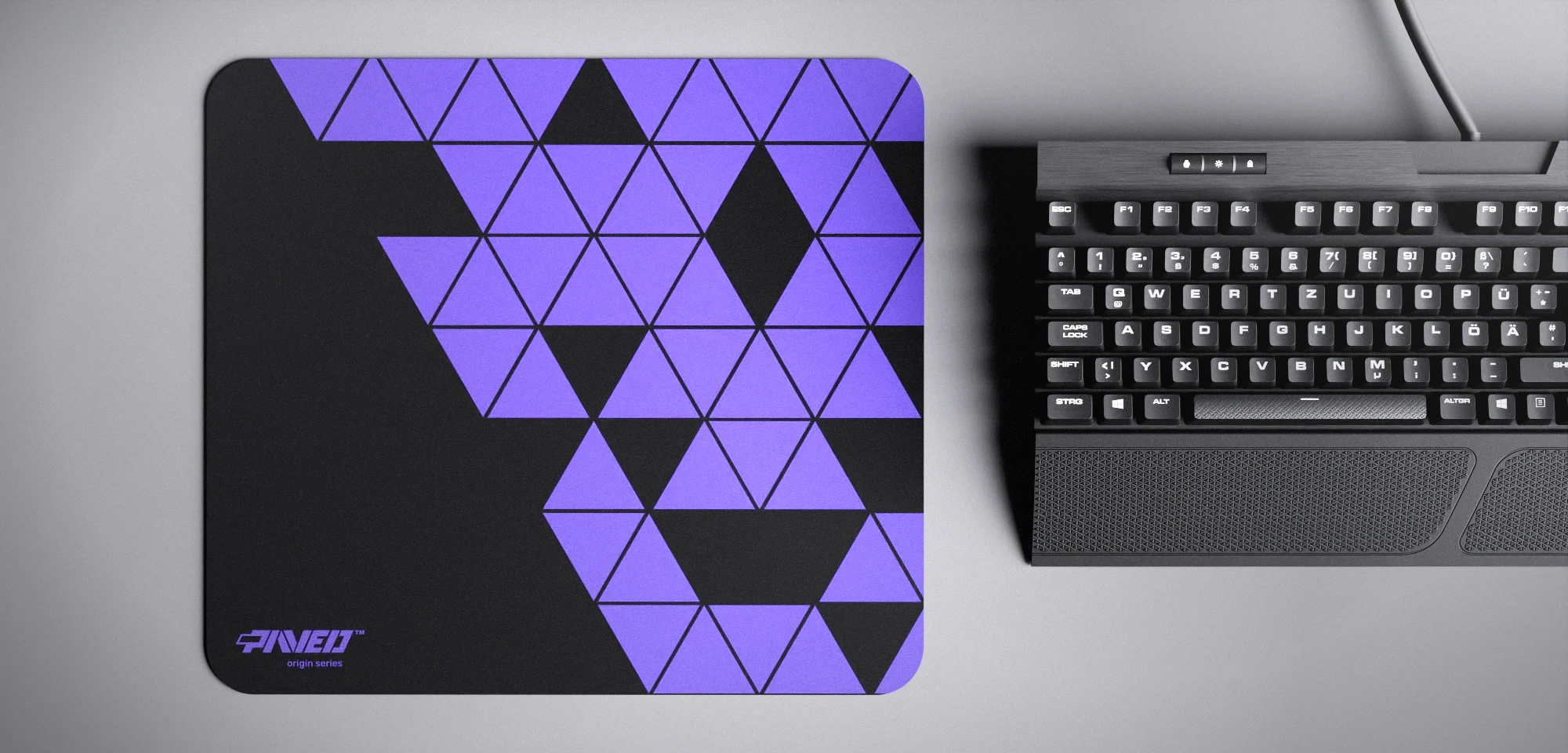 Top view of Night Amethyst Prism M size mousepad 360mm x 320mm left-handed variant with minimalistic purple triangular prism pattern on black background, water-resistant antimicrobial polyester surface, shown with full-size mechanical keyboard for scale, ultra-lightweight odour-free AreoFlex base, stitch-free edges.