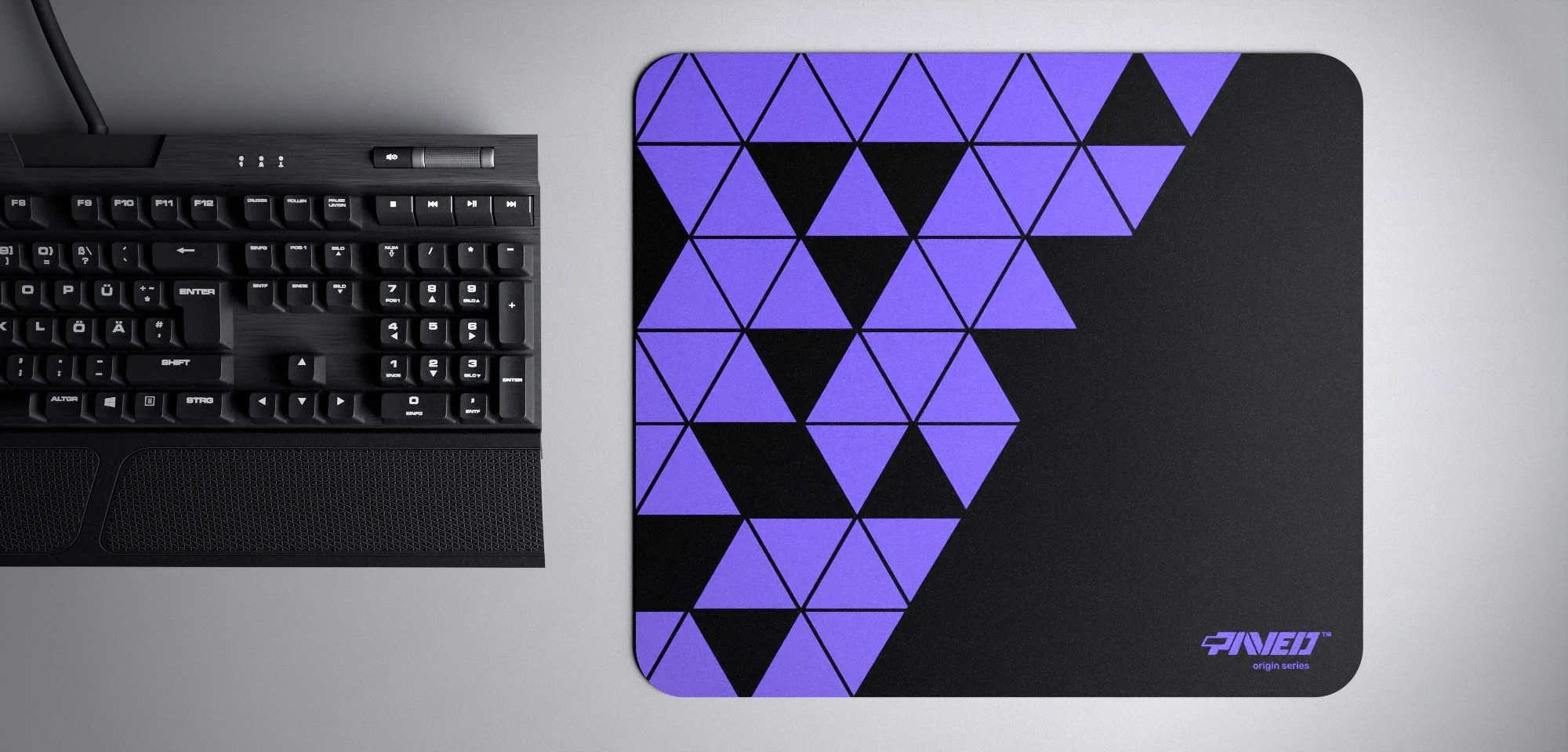 Top view of Night Amethyst Prism M size mousepad 360mm x 320mm right-handed variant with geometric purple and black triangular pattern, hydrophobic easy-to-clean surface with antimicrobial properties, shown with full-size mechanical keyboard for scale, 600% lighter with no rubbery odour base, durable stitch-free finish.