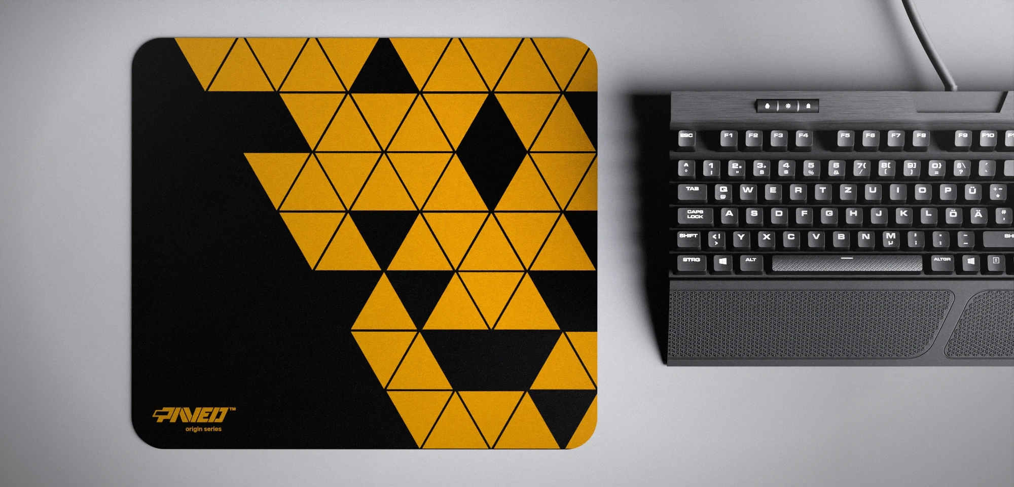 Top view of Night Desert Prism M size mousepad 360mm x 320mm left-handed variant with minimalistic deep yellow triangular prism pattern on black background, water-resistant antimicrobial polyester surface, shown with full-size mechanical keyboard for scale, ultra-lightweight odour-free AreoFlex base, stitch-free edges.