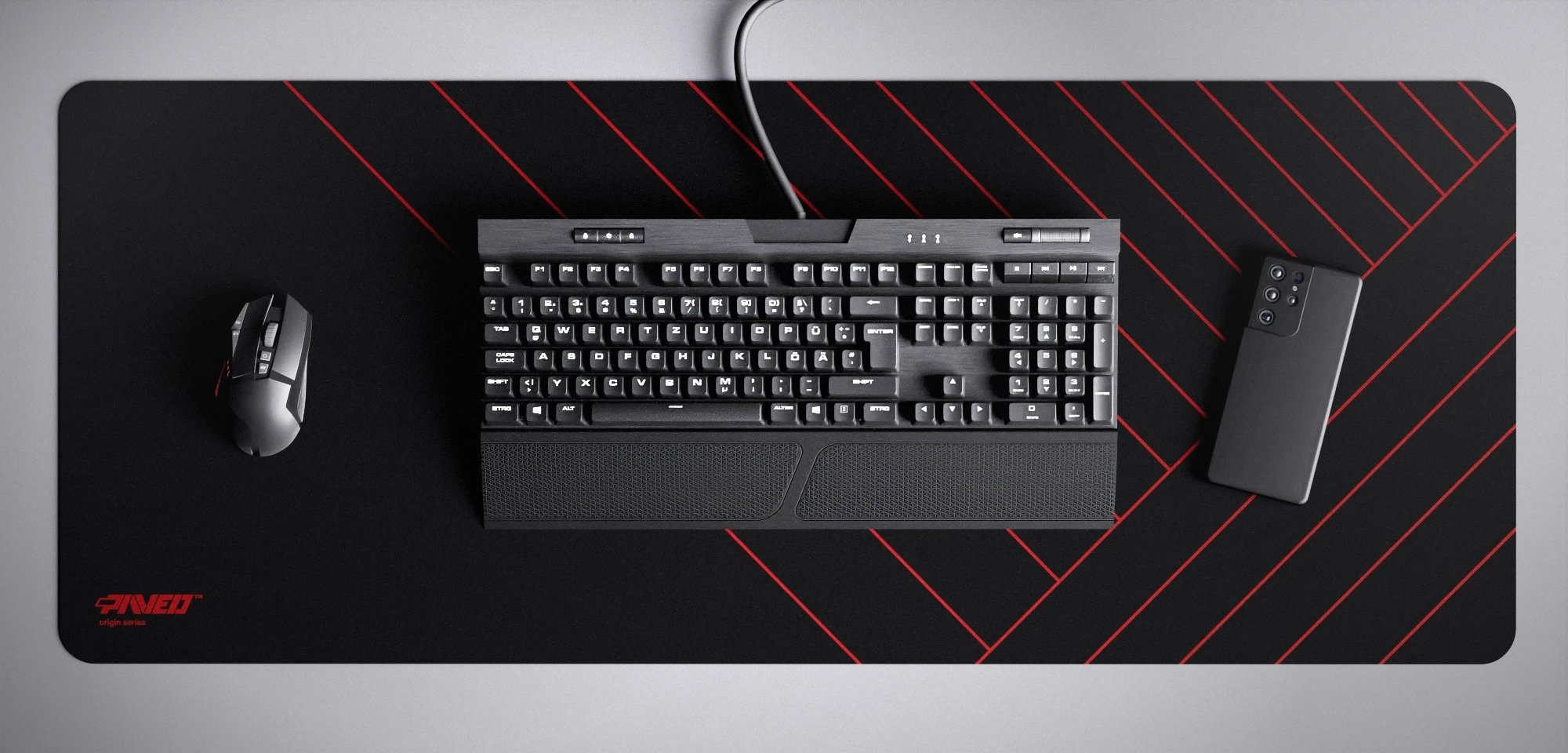 Top view of Night Imperial Zebra XXL deskmat 1000mm x 400mm left-handed variant featuring diagonal stripe pattern in red and black, water-resistant antimicrobial polyester surface, shown with full-size mechanical keyboard, gaming mouse, and smartphone for scale, ultra-lightweight odour-free AreoFlex microruber base, stitch-free professional finish.