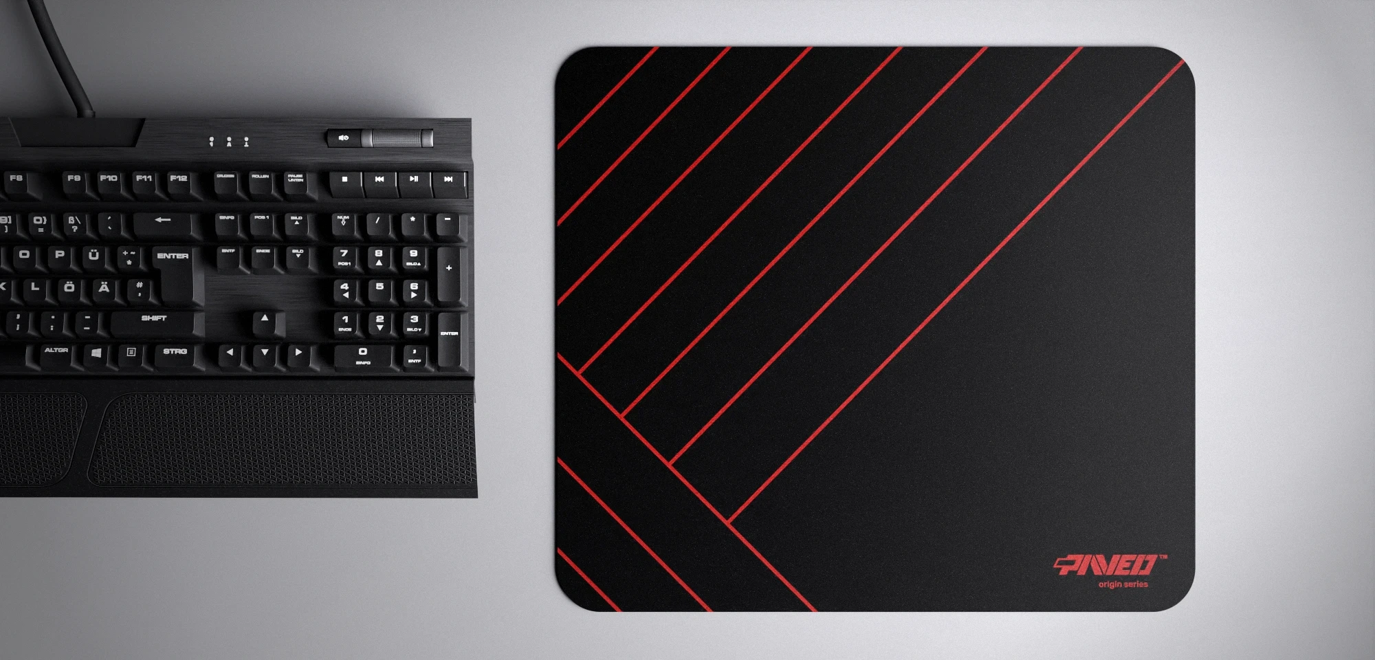 Top view of Night Imperial Zebra M size mousepad 360mm x 320mm right-handed variant with diagonal stripe pattern in red and black, hydrophobic easy-to-clean surface with antimicrobial properties, shown with full-size mechanical keyboard for scale, 600% lighter with no rubbery odour base, durable stitch-free finish.
