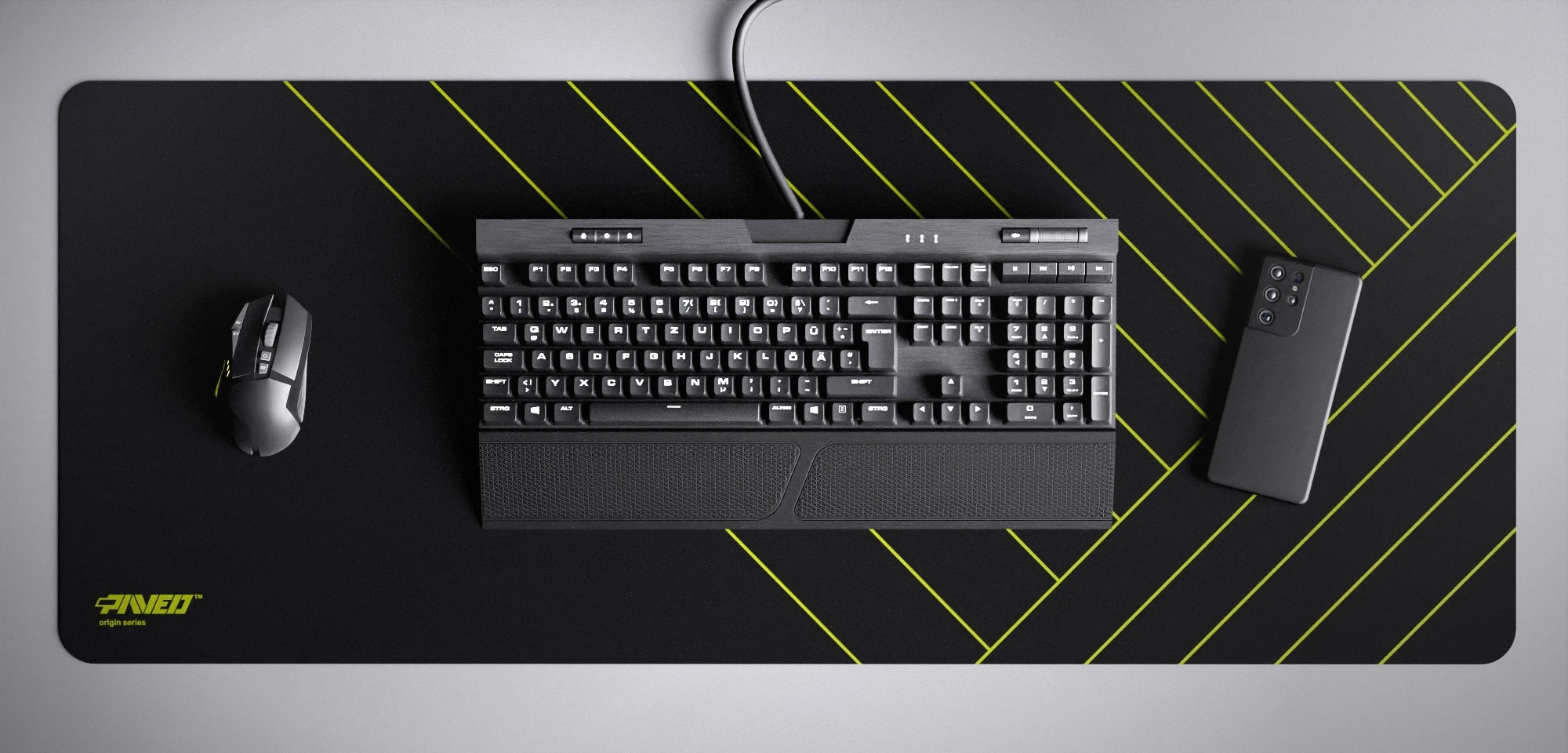 Top view of Night Toxic Zebra XXL deskmat 1000mm x 400mm left-handed variant featuring diagonal stripe pattern in light green and black, water-resistant antimicrobial polyester surface, shown with full-size mechanical keyboard, gaming mouse, and smartphone for scale, ultra-lightweight odour-free AreoFlex microruber base, stitch-free professional finish.