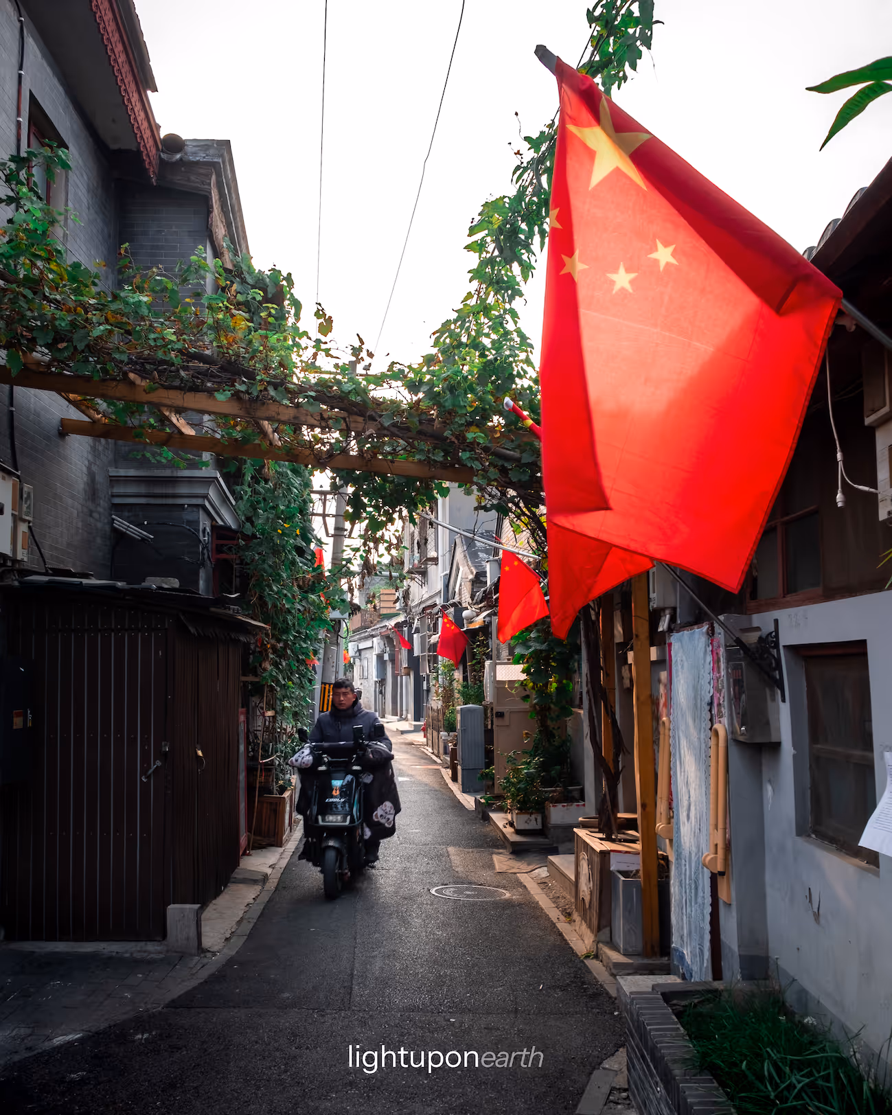 Man on a scooter driving through a Hutong