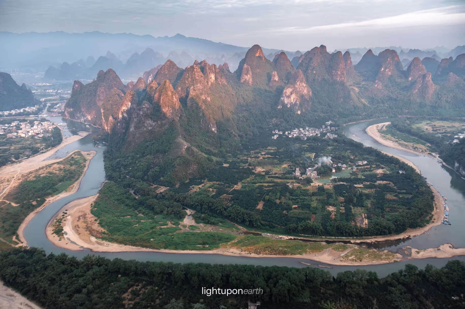 Winding river with karst mountains lit up by the last sunrays in the background