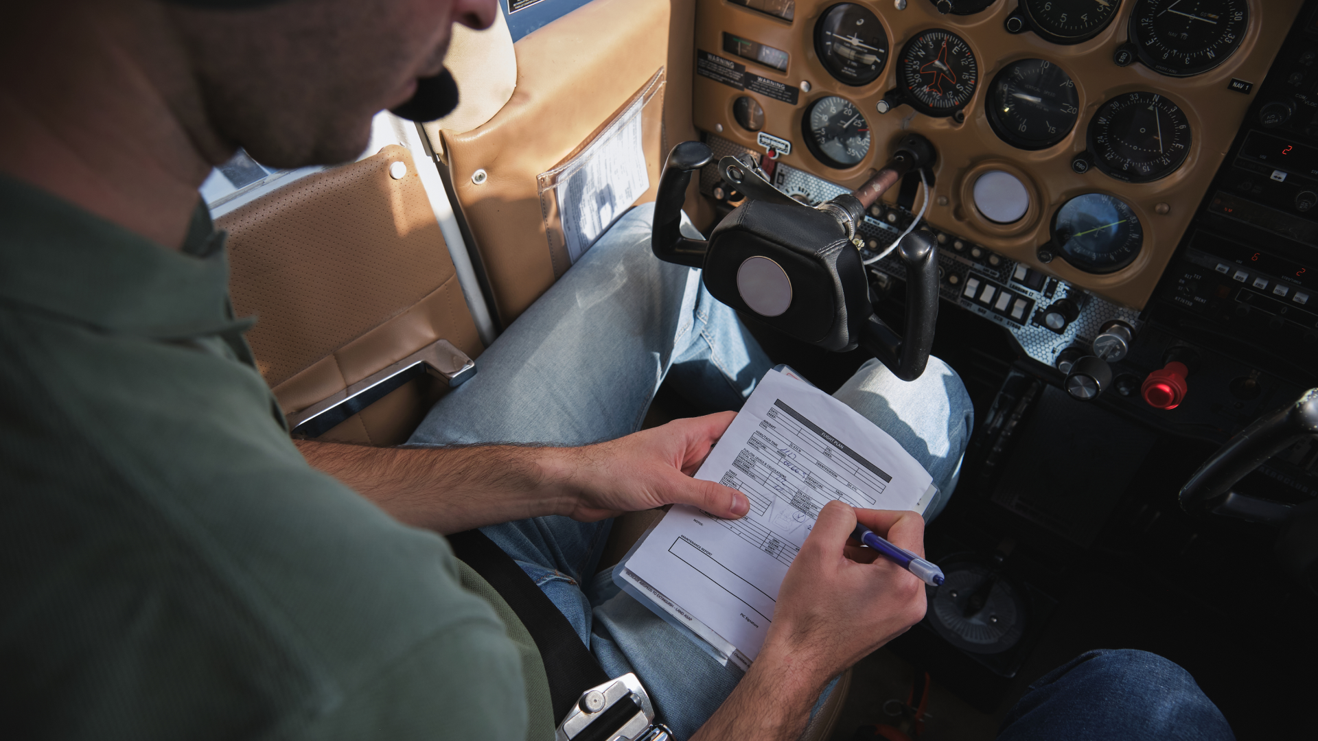 Pilot completing aircraft logbook paperwork inside cockpit during flight operations.