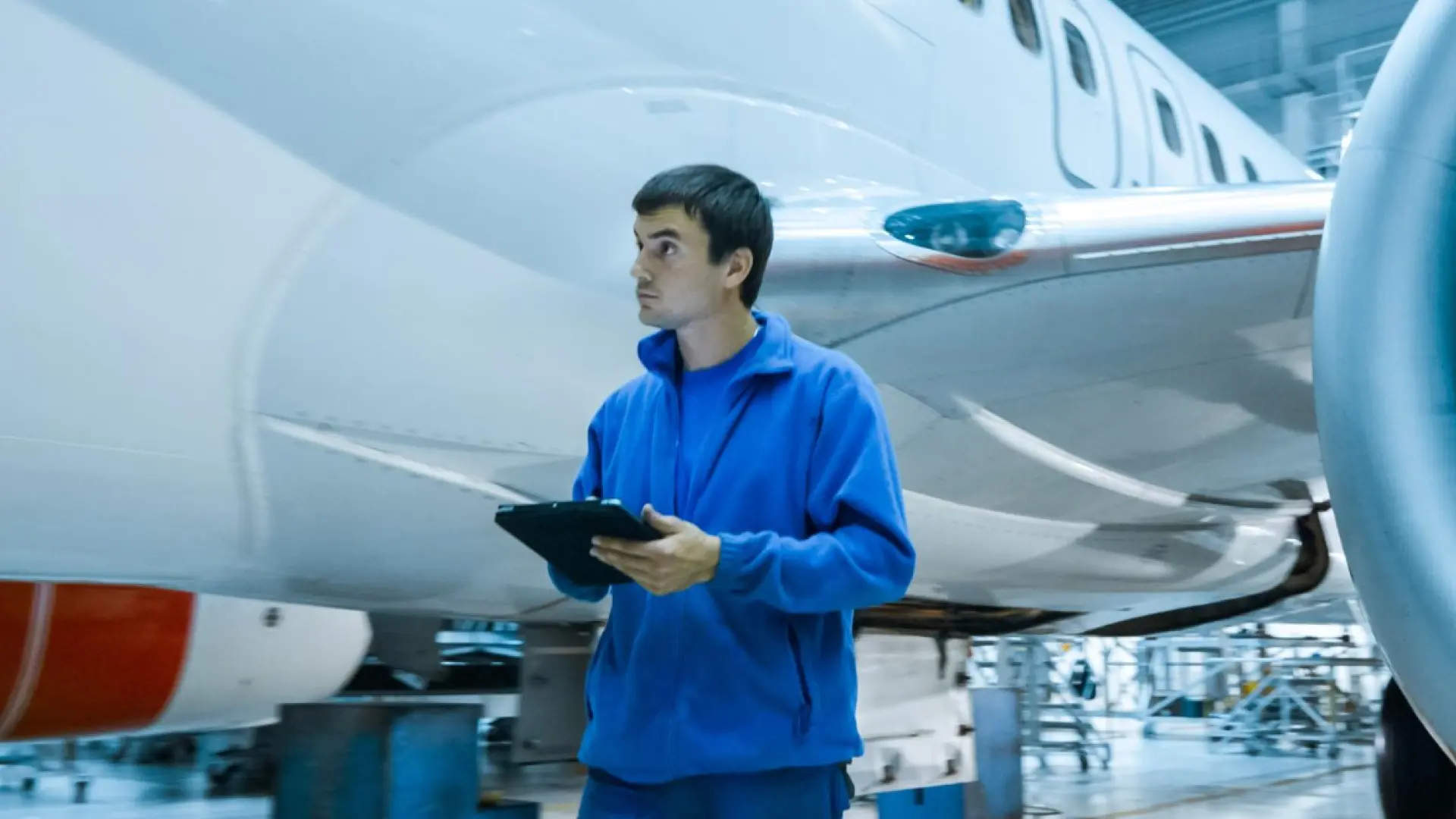 Maintenance personnel reviewing compliance records and documentation alongside an aircraft in a hangar.