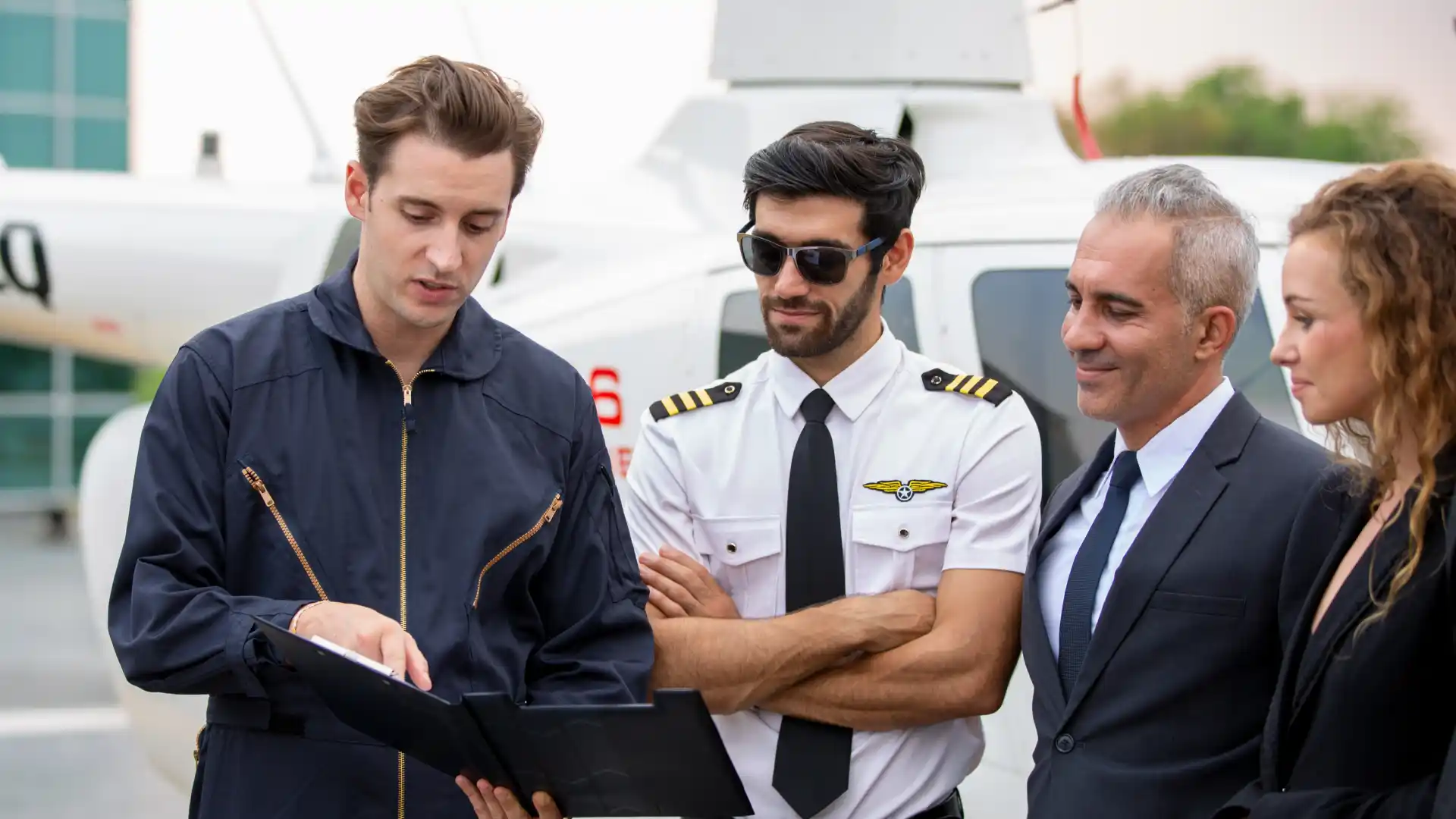 A group of aviation professionals, including a pilot and inspectors, standing beside a helicopter while reviewing documents during an inspection briefing.