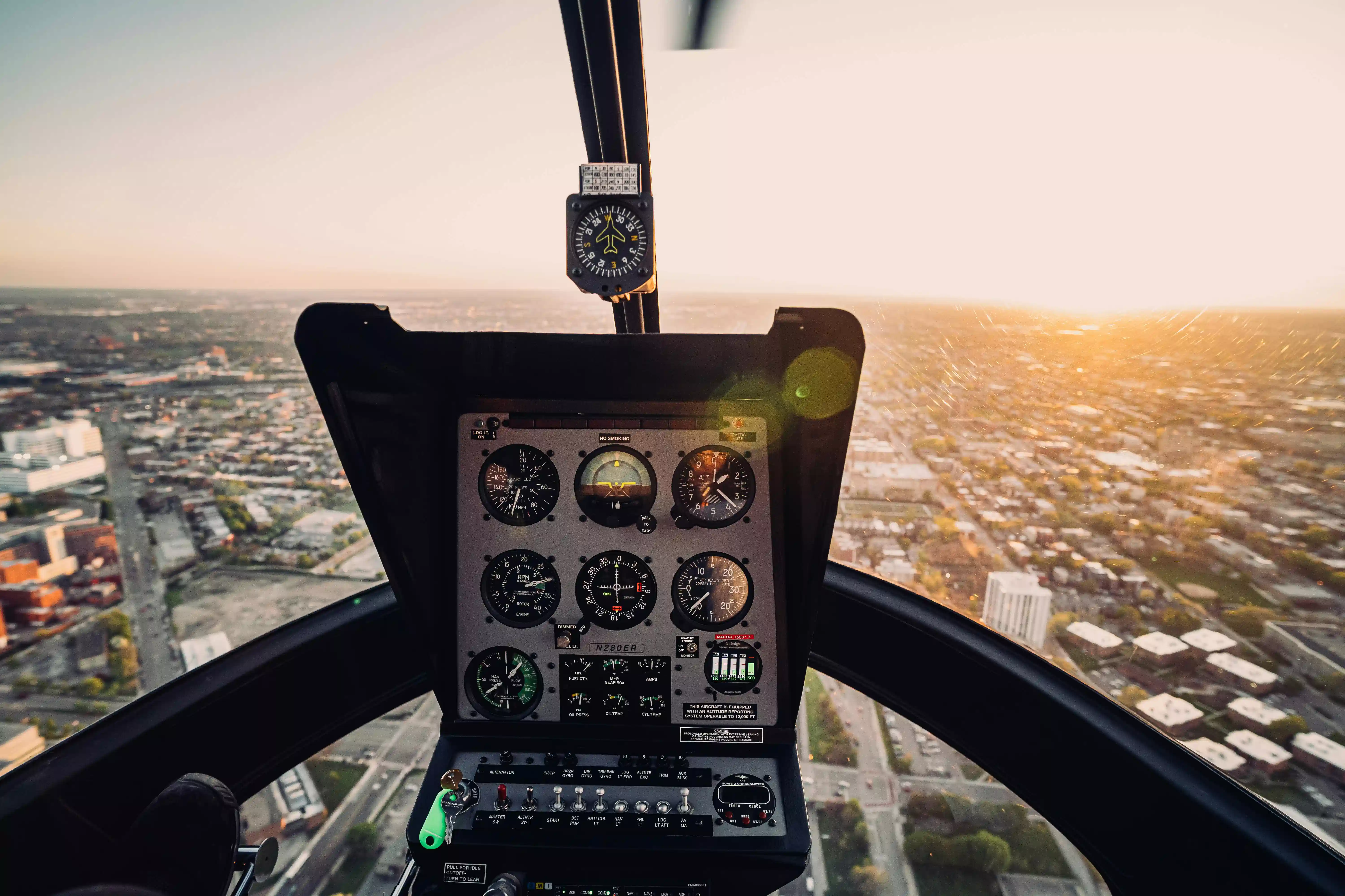 An aircraft cockpit with several navigation instruments, flying over a large city at dusk.