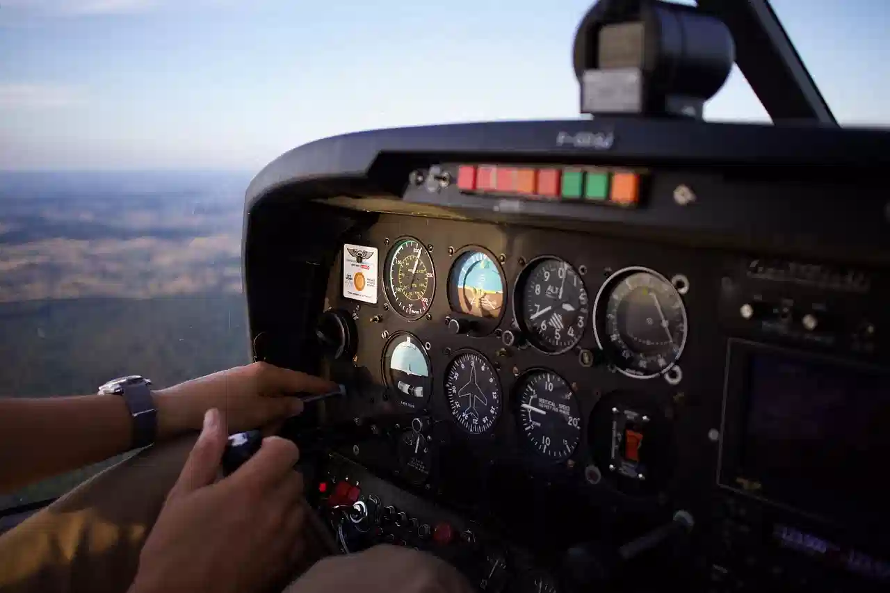 A pilot uses the operating controls in a small aircraft cockpit, surrounded by analogue gauges and instruments.