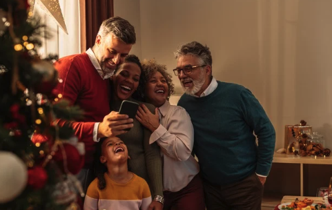A man and woman are seated with their legs crossed, stretching their left arms up and extending them to the right side of their bodies.
