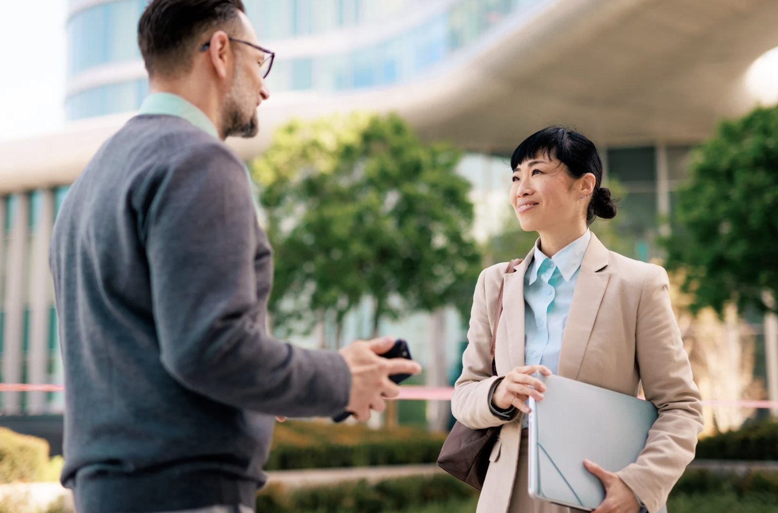 A man and woman are seated with their legs crossed, stretching their left arms up and extending them to the right side of their bodies.