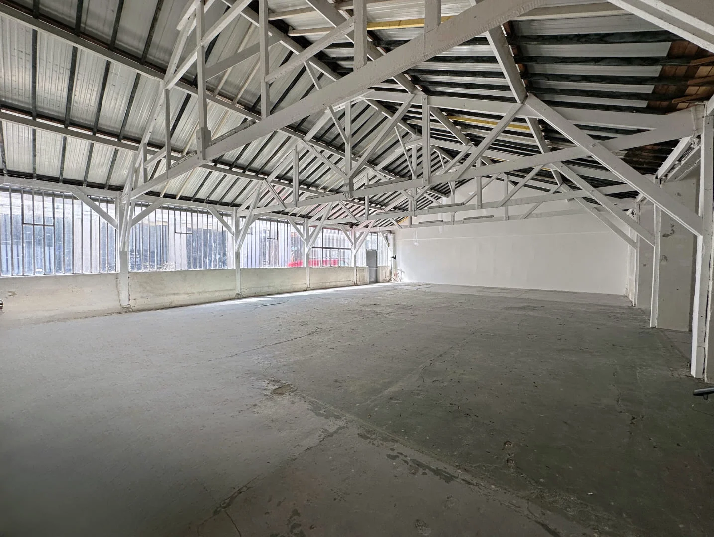 Espace créatif de l'Atelier des Lumières chez Artefact Paris, montrant un mur blanc utilisé pour la peinture, une échelle en bois et des œuvres d'art colorées, éclairé par une lumière naturelle venant de grandes fenêtres.