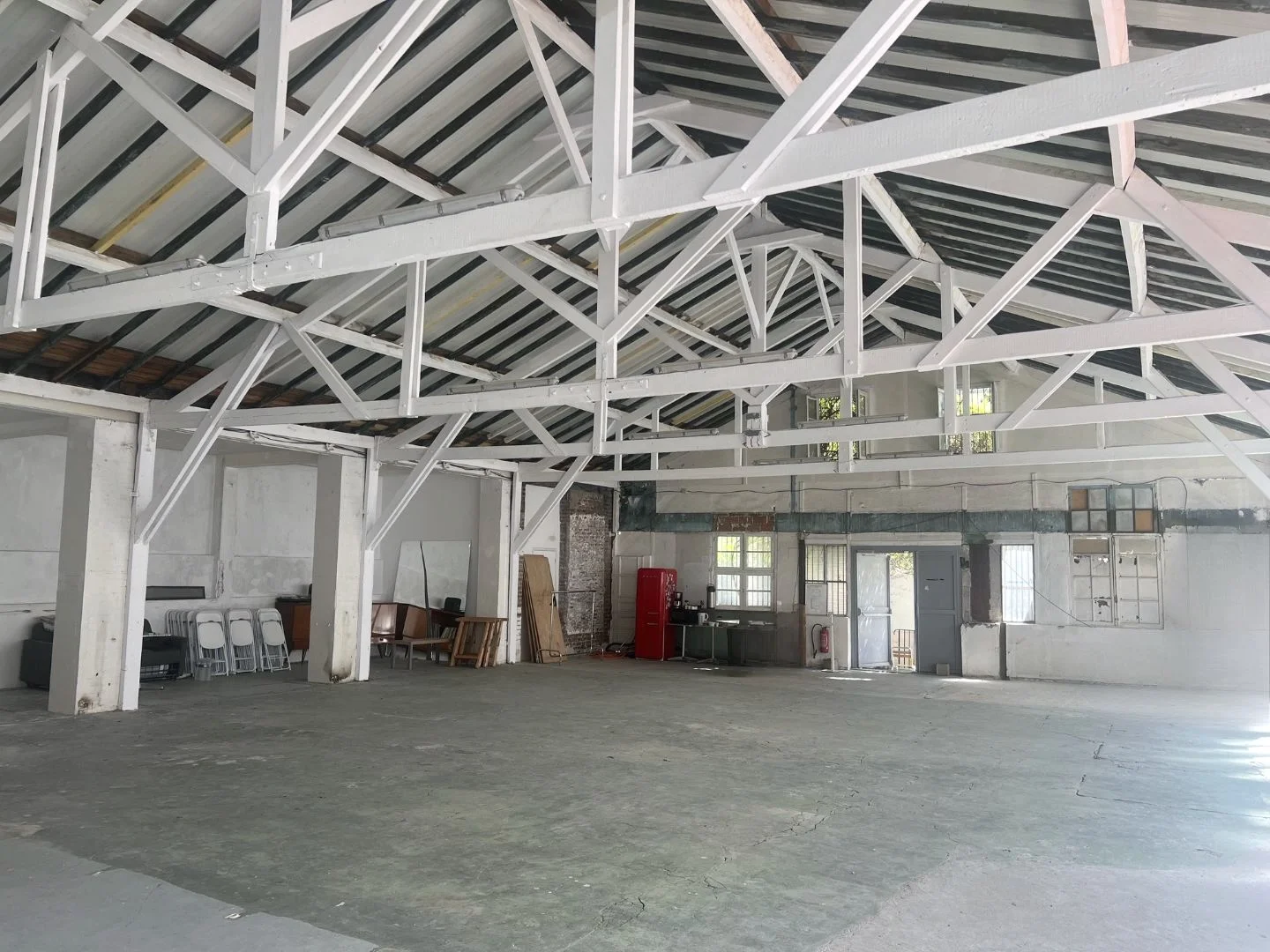 Loft spacieux et éclairé d'Artefact Paris avec rideaux contrastants, parquet ancien et grandes fenêtres offrant une luminosité naturelle, parfait pour des événements créatifs à l'Atelier des Lumières