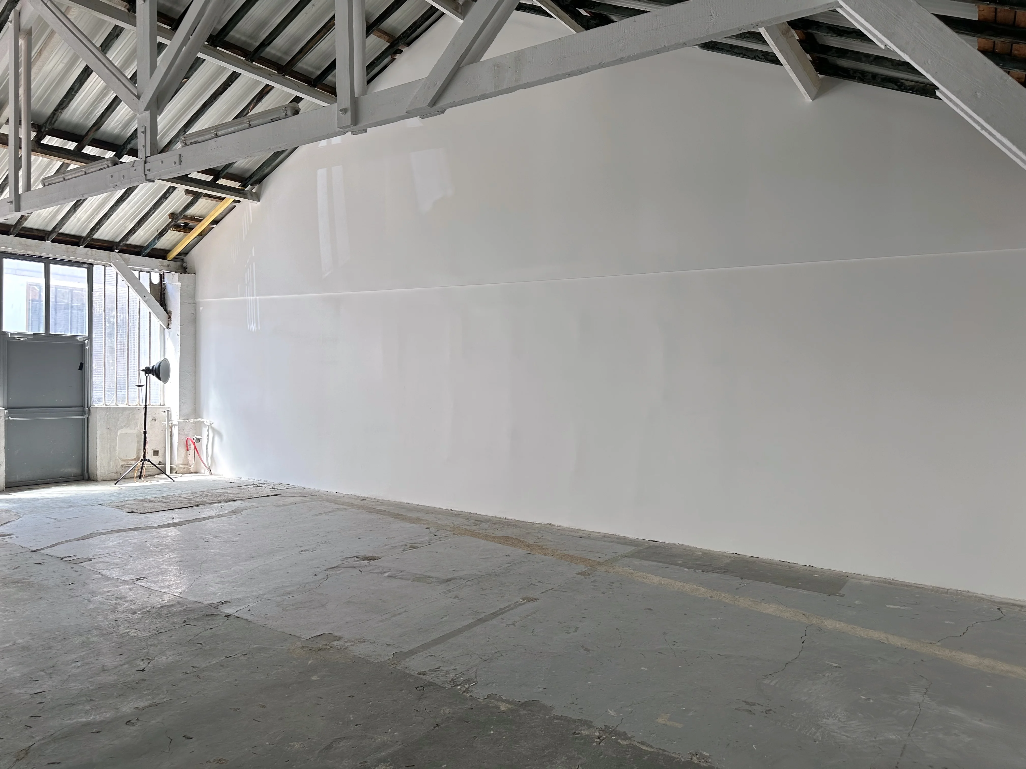 Espace artistique de l'Atelier des Lumières chez Artefact Paris, avec une échelle en bois appuyée contre un mur éclaboussé de peinture, évoquant la créativité et l'histoire du lieu