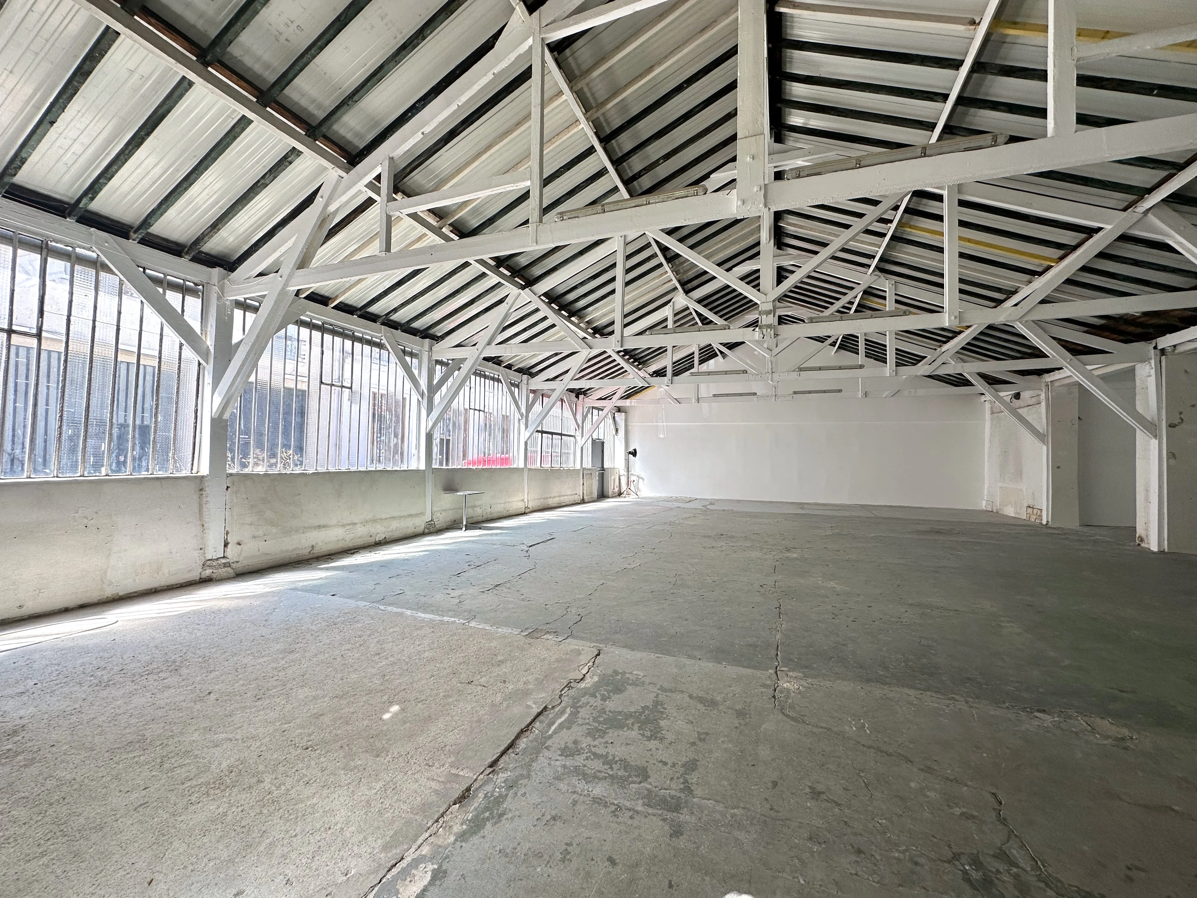 Vue intérieure de l'Atelier sur Cour chez Artefact Paris, soulignant son vaste espace épuré de 100m² avec des murs blancs et un sol en béton brut, idéal pour des séances photo ou des expositions.