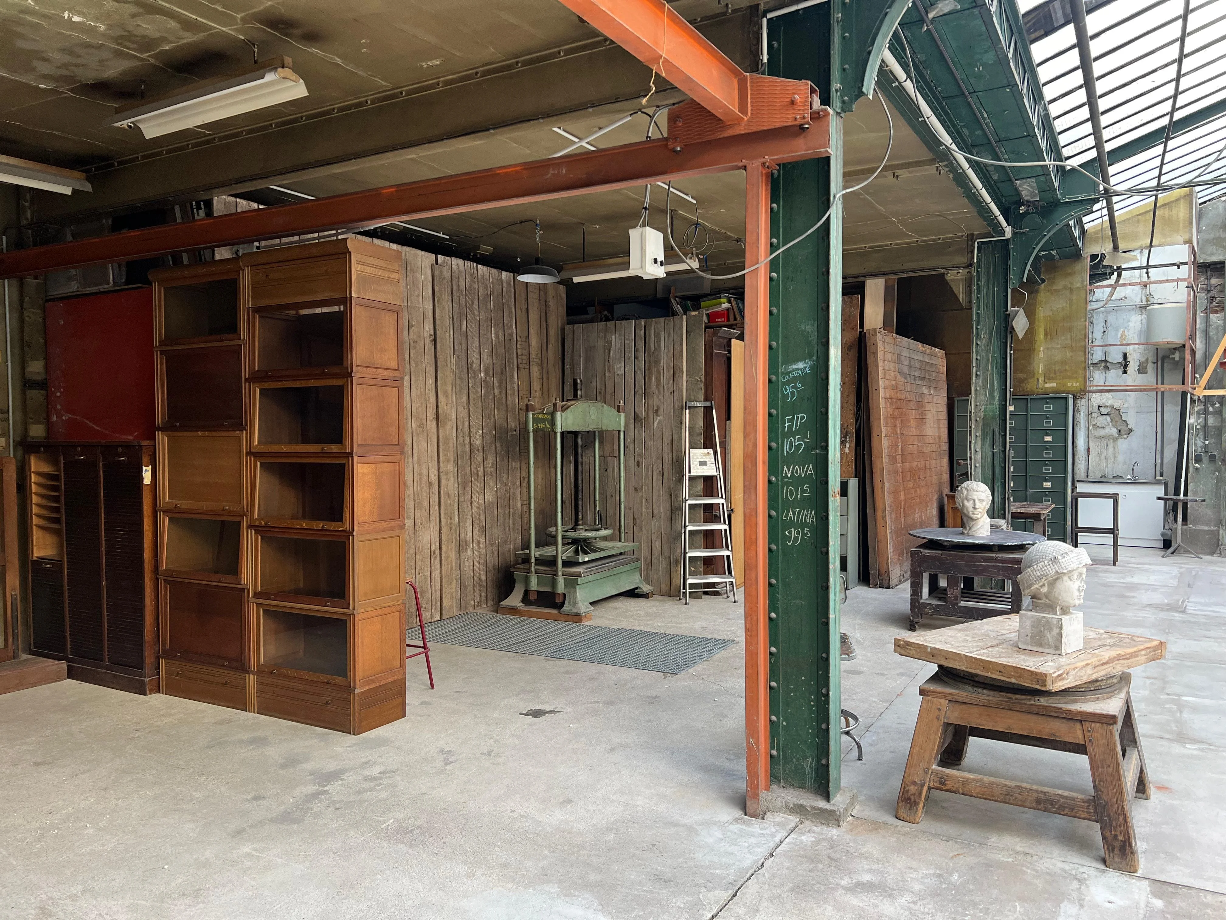 Vue d'angle atelier eiffel avec statues et miroir, ambiance artistique.