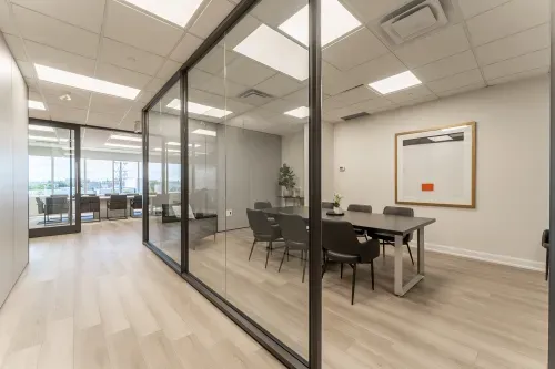 A series of hallways with offices separated by glass walls. A large boardroom is at the back and a smaller boardroom is to the right.