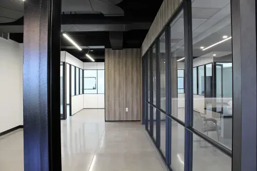 A white hallways with white, glass and black metal walls and shiny grey concrete floors.