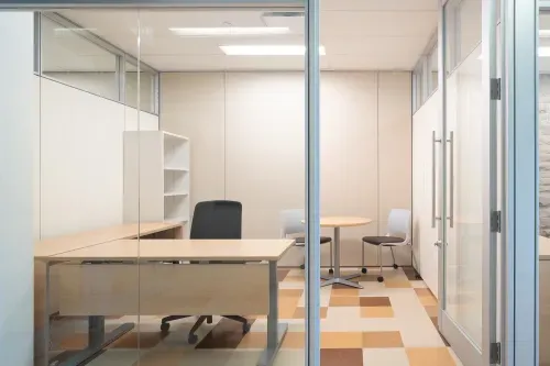 Spacious office with large desk, seating area, and floor-to-ceiling glass wall