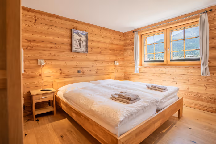Double bedroom with pine walls and alpine mountain views at Chalet Furi Zermatt