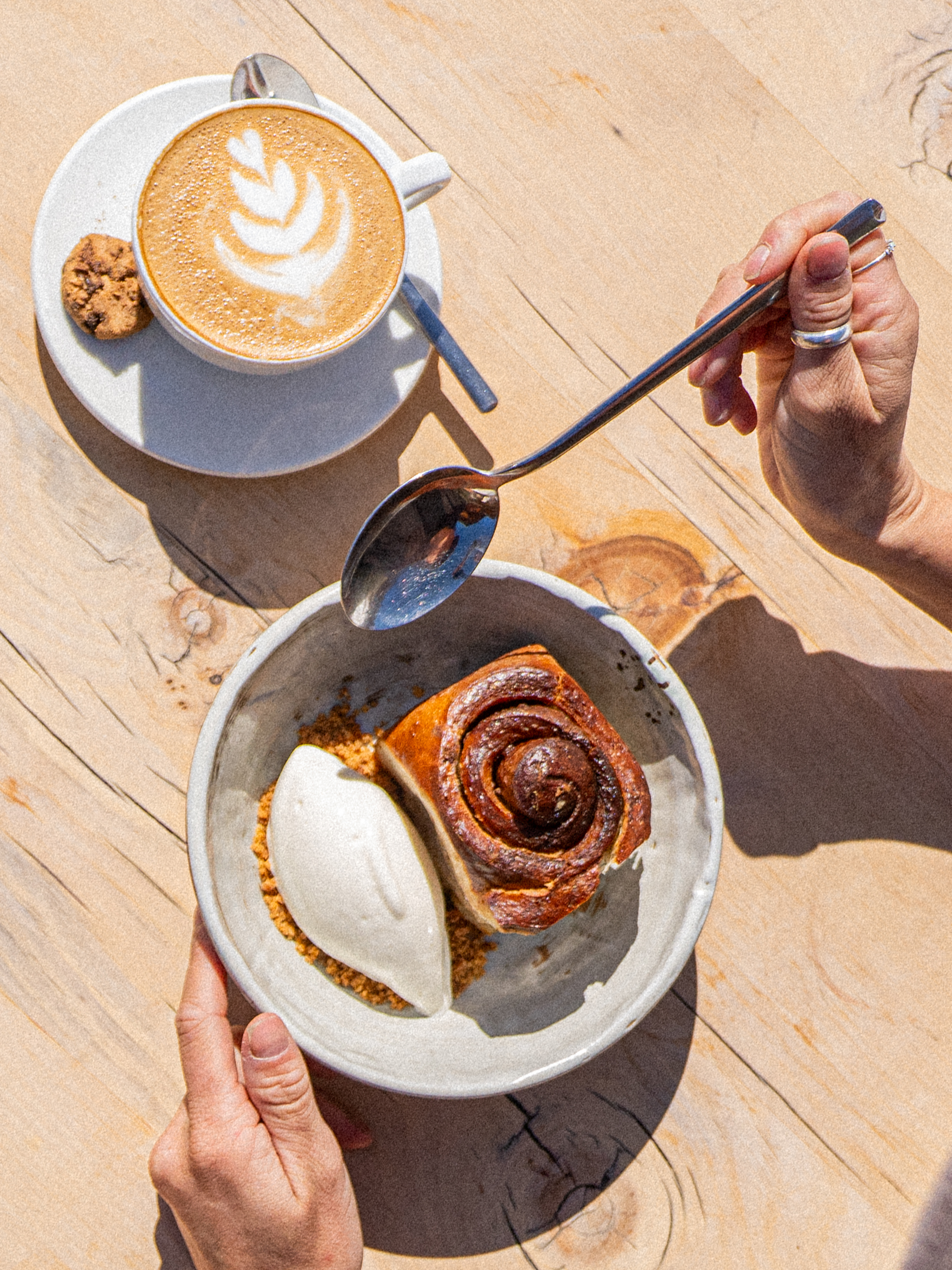 Frischer Zimtknoten mit Fior di Latte und Cappuccino mit Latte-Art auf Holztisch, Frühstück auf der Terrasse des MARMO, Furi Zermatt