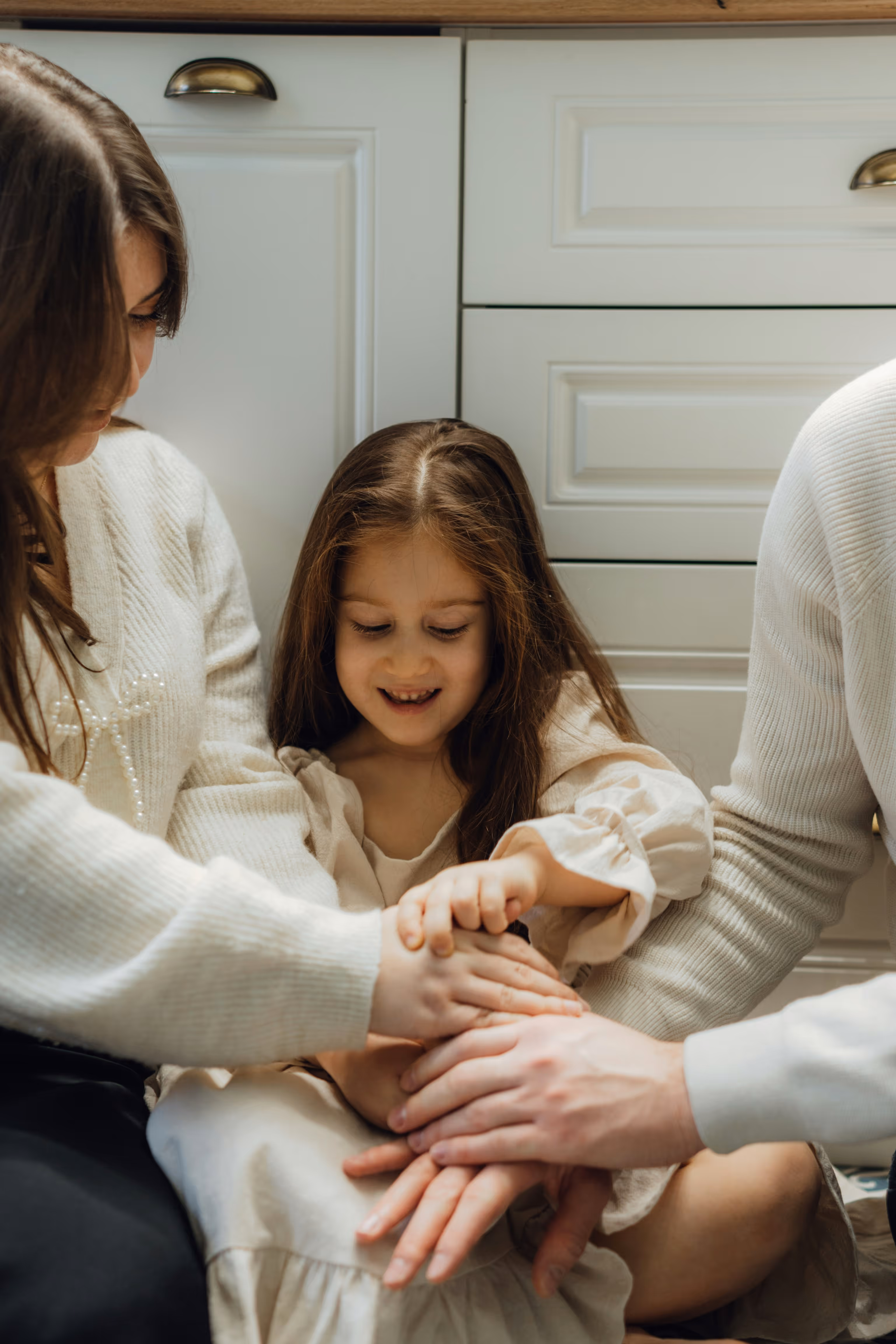 Family members joining hands together with a young girl smiling between them