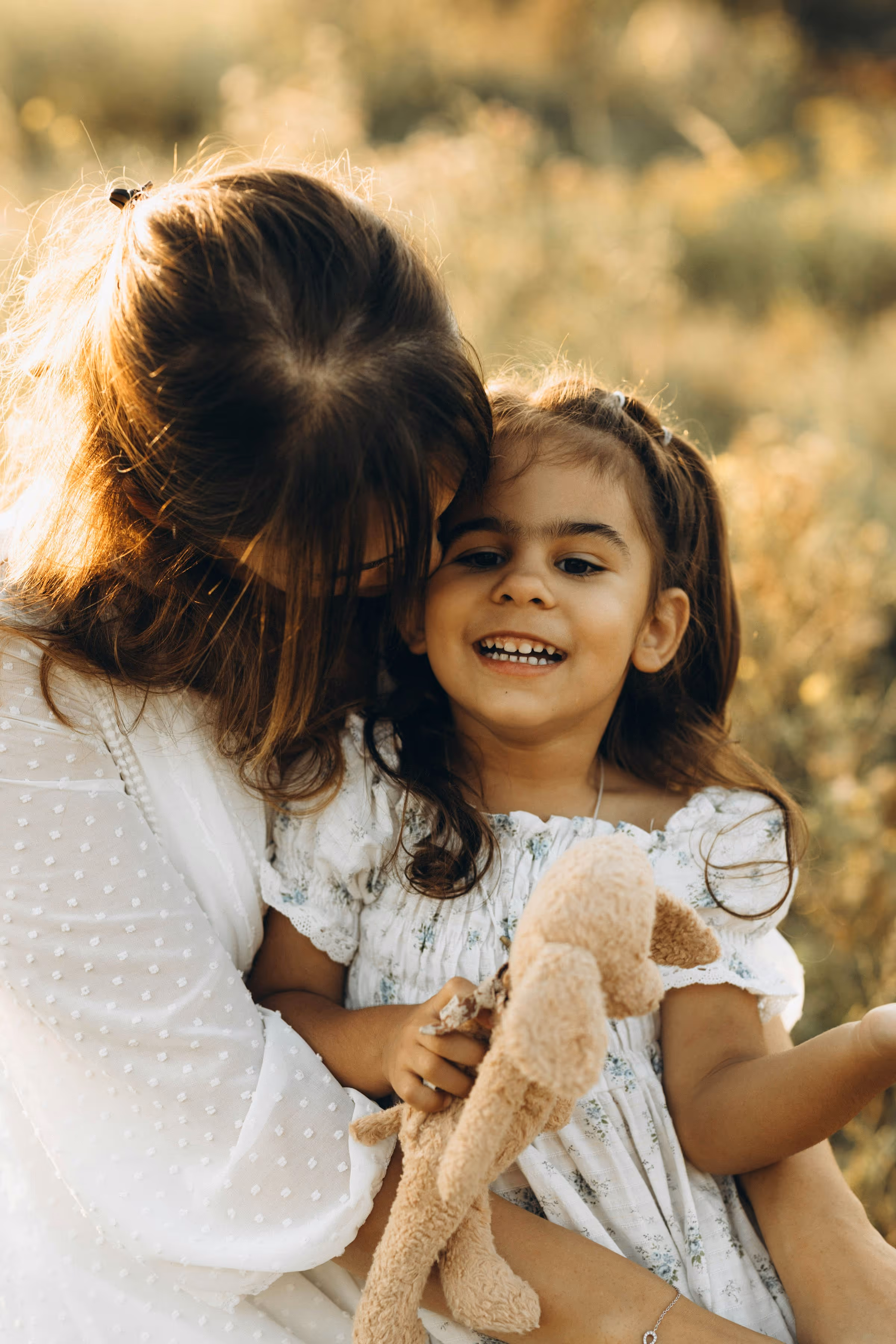 Mom holding her daughter as they spend time together outside.