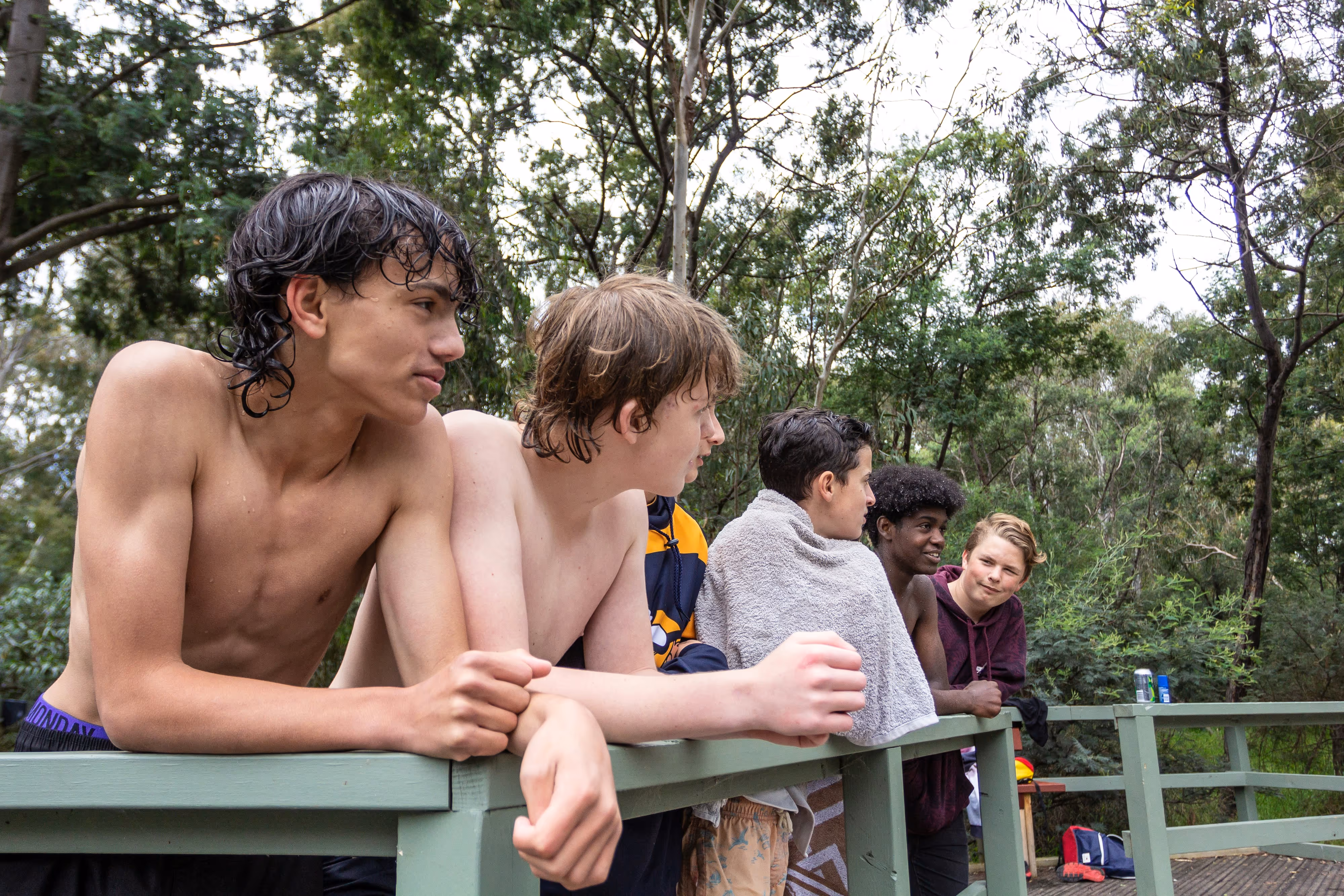 Group of teenagers of diverse backgrounds standing together on a wooden bridge