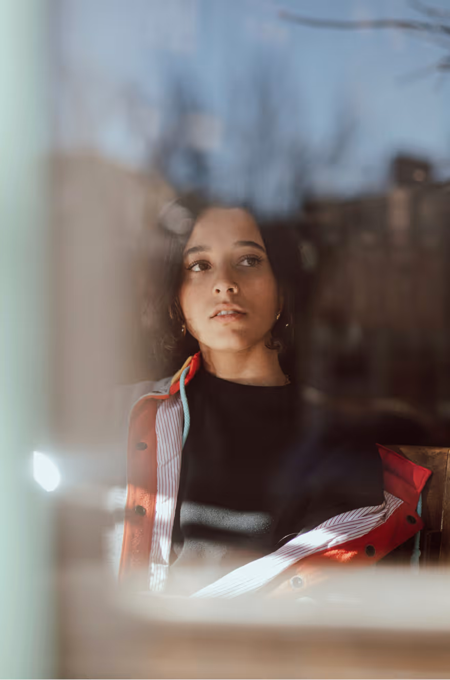 Young woman with short bob gazing thoughtfully through a sunlit window