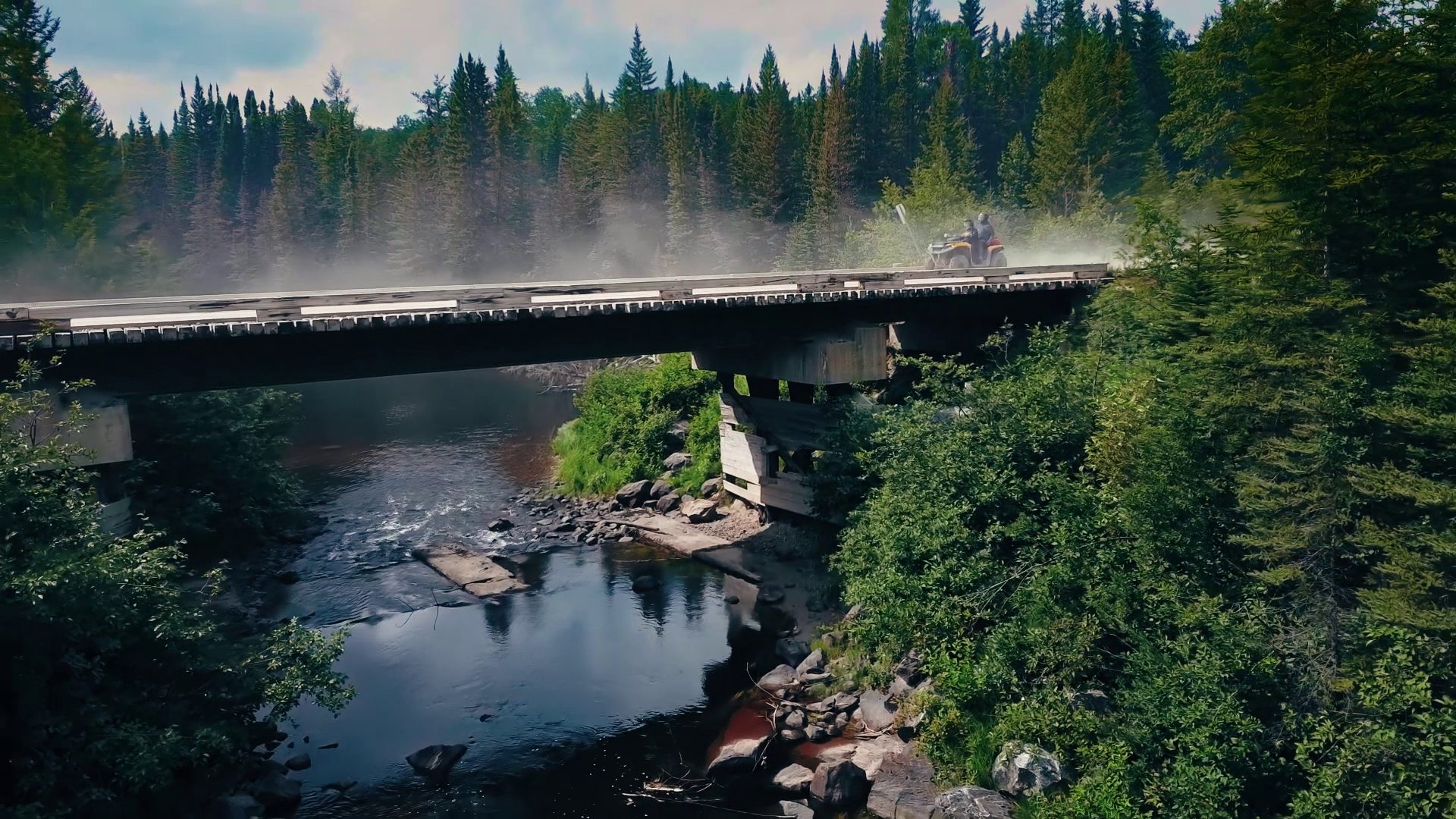 A side-by-side crosses the wooden bridge over the rapids on the Jamboree route