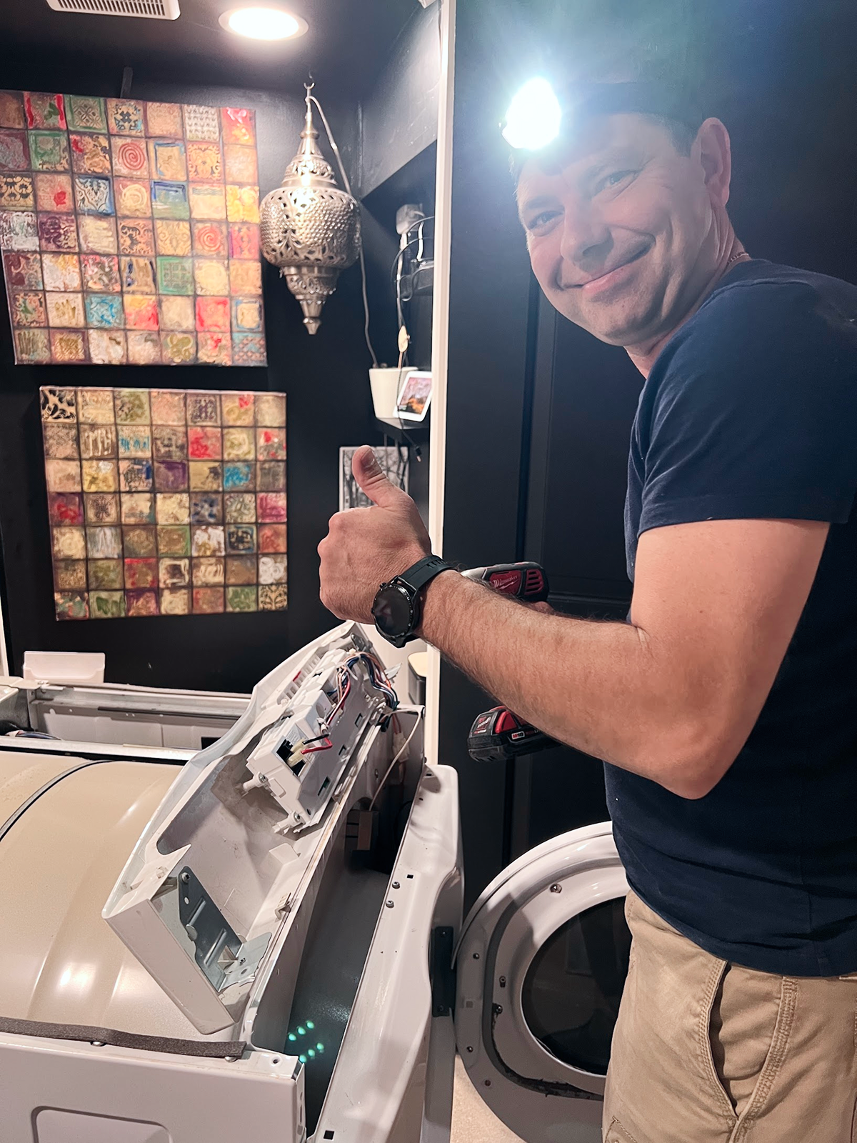 Technician repairing a front-load dryer during an in-home appliance repair service in Chicago area home.