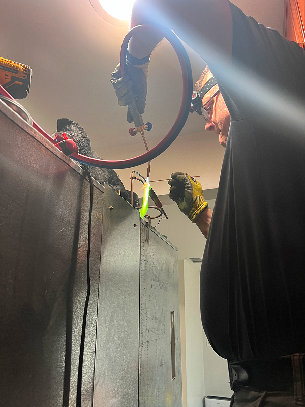 Technician brazing and repairing copper refrigeration lines