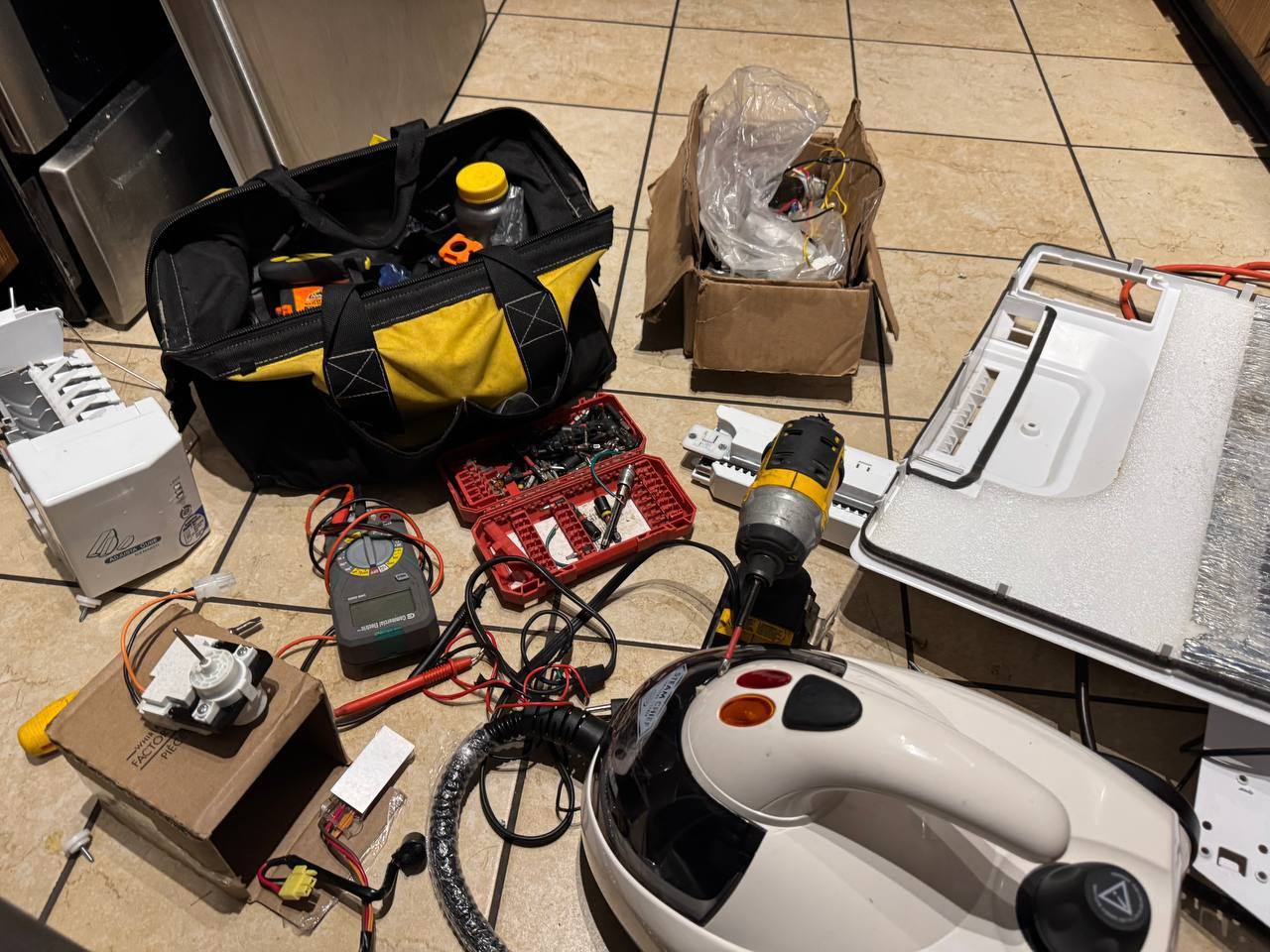 Appliance repair tools and replacement parts on kitchen floorTechnician repairing dishwasher panel with power drill