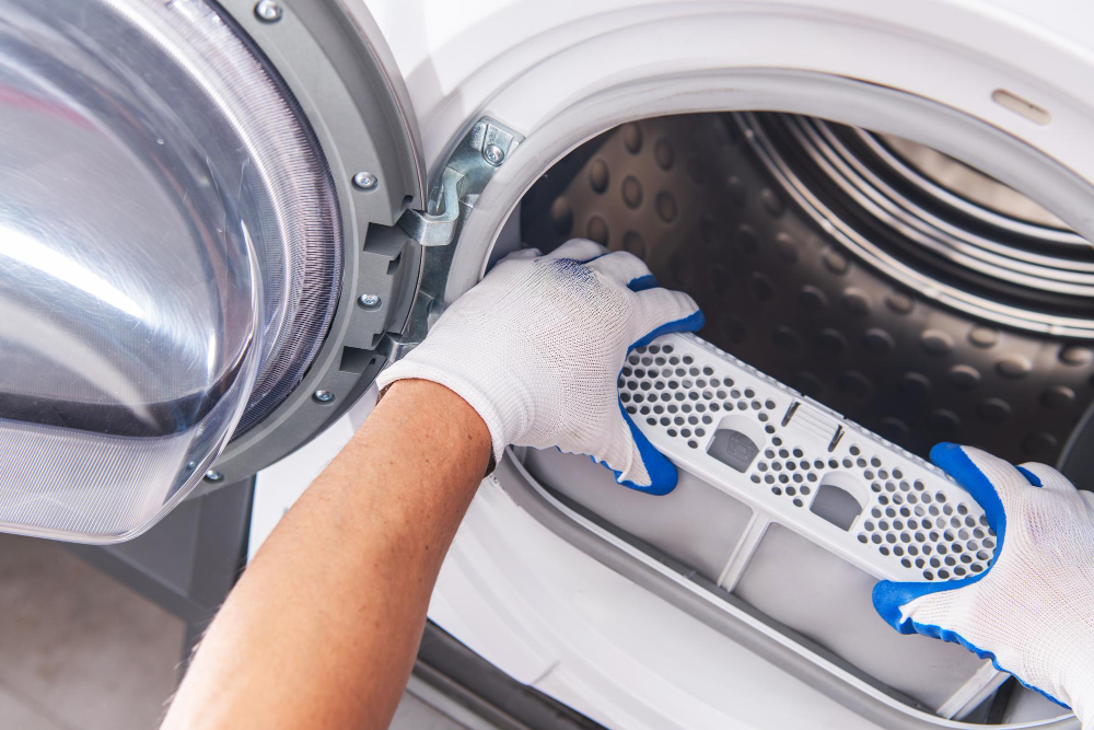 Technician cleaning dryer lint filter during routine dryer maintenance service
