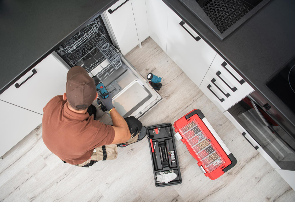 Appliance repair technician installing built in dishwasher under kitchen counter