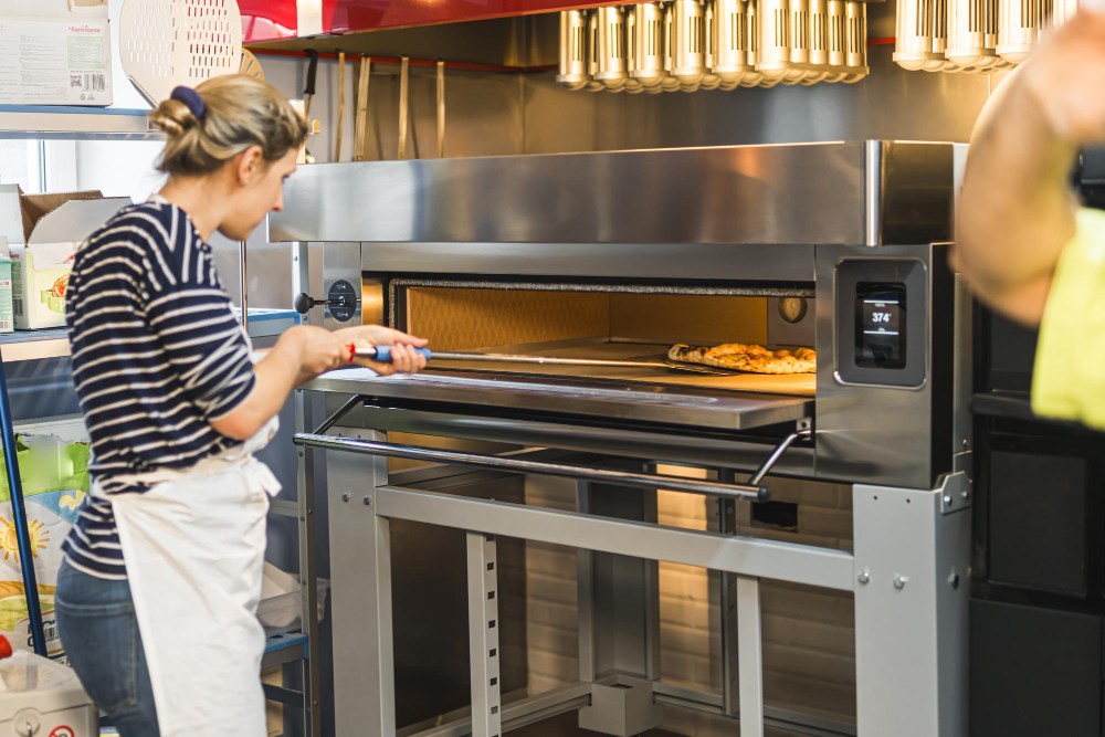 restaurant worker cooking pizza in a commercial oven
