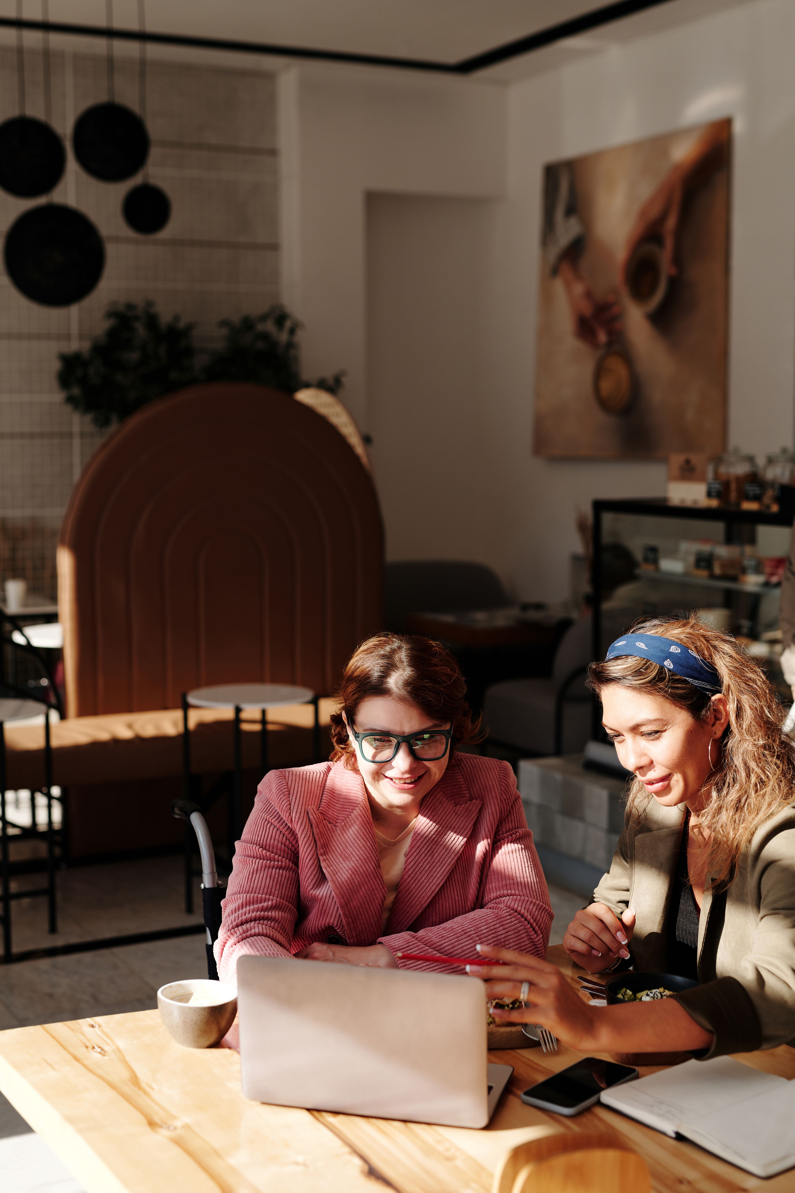 Two women smiling and talking over coffee at a café