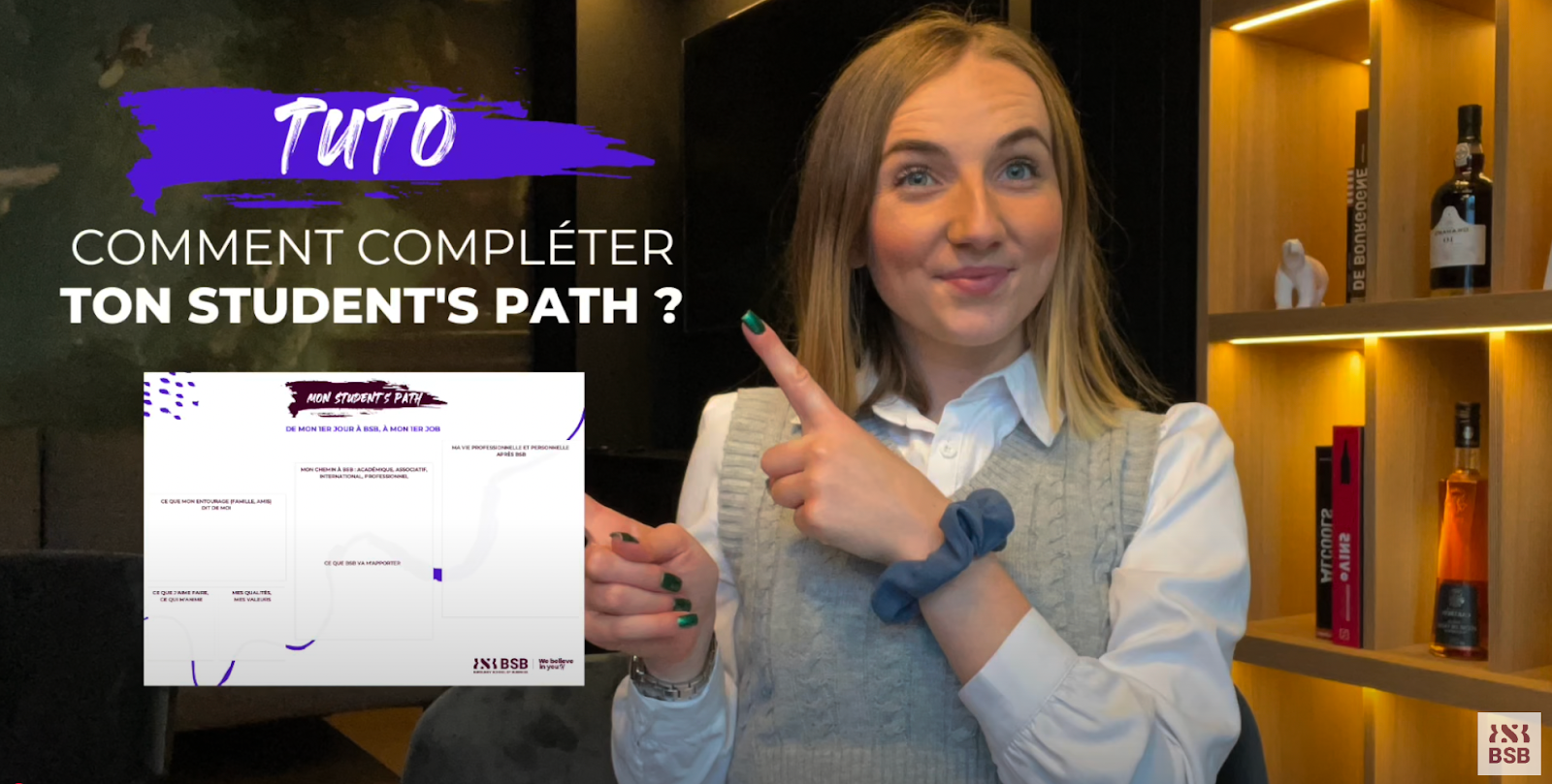 Étudiante souriante pointant vers un tuto “Comment compléter ton Student’s Path ?” sur fond sombre avec étagère éclairée – BSB