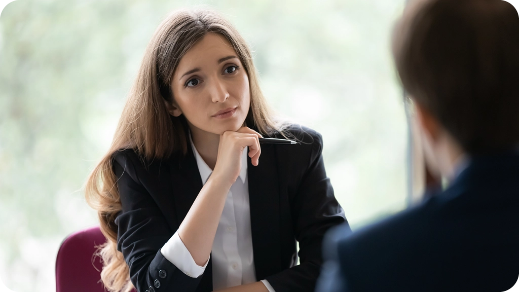 Jeune femme en costume professionnel écoutant attentivement un candidat lors d’un entretien, symbolisant le rôle de gestion et de recrutement d’un futur DRH – BSB