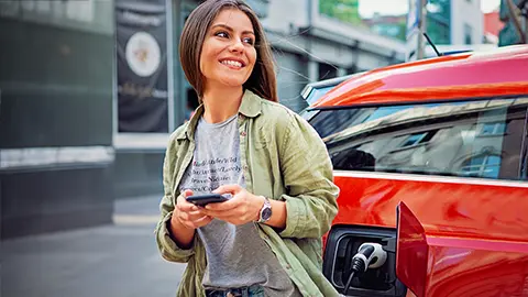 Woman standing by her charging EV