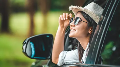 Lady wearing sunglasses and weaved had looking out of car window